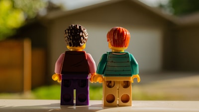 Two lego figures holding hands in front of house
