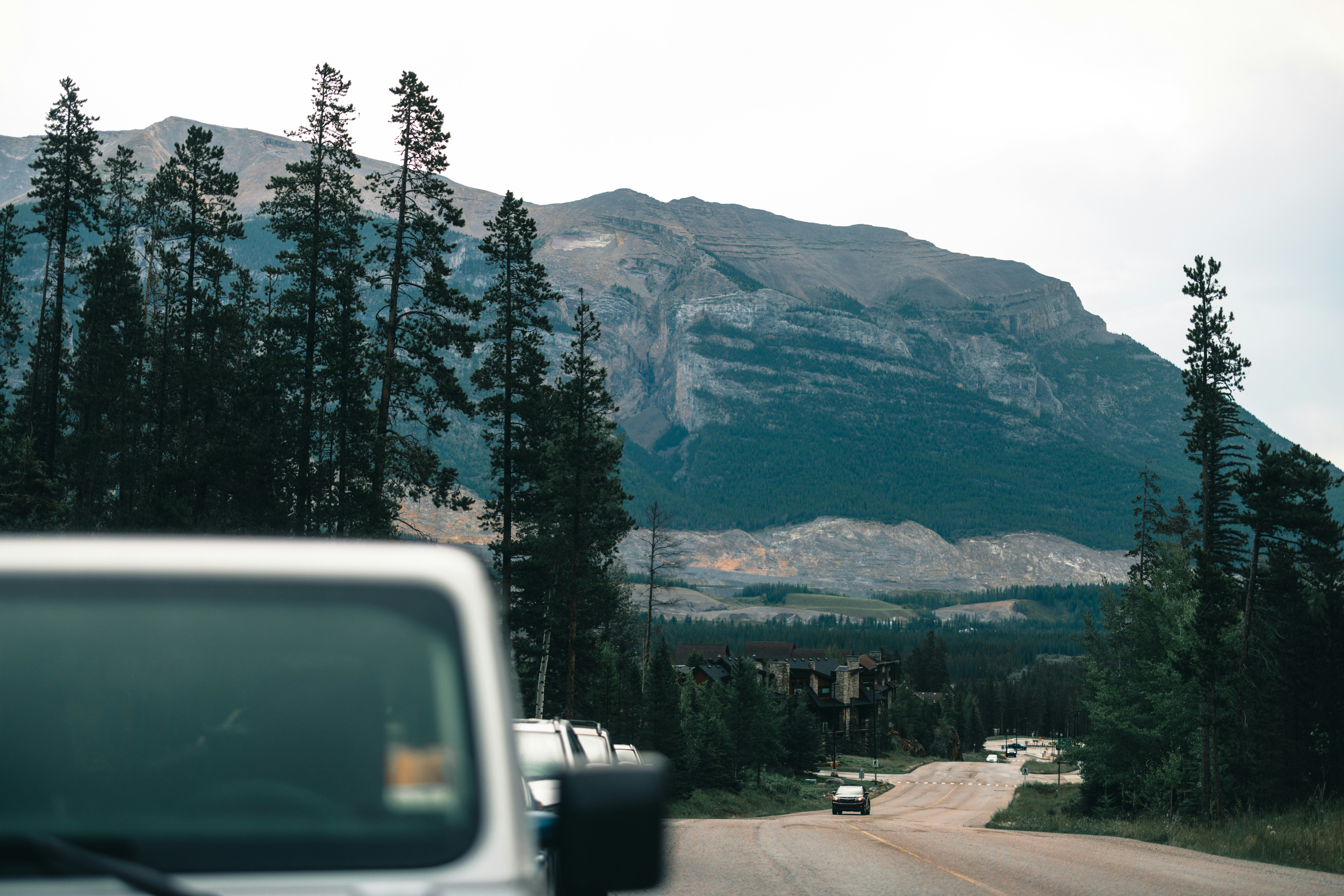 A sleek electric vehicle driving on a modern Canadian highway with a backdrop of city and nature