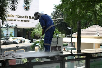 Worker pressure washing a surface outdoors