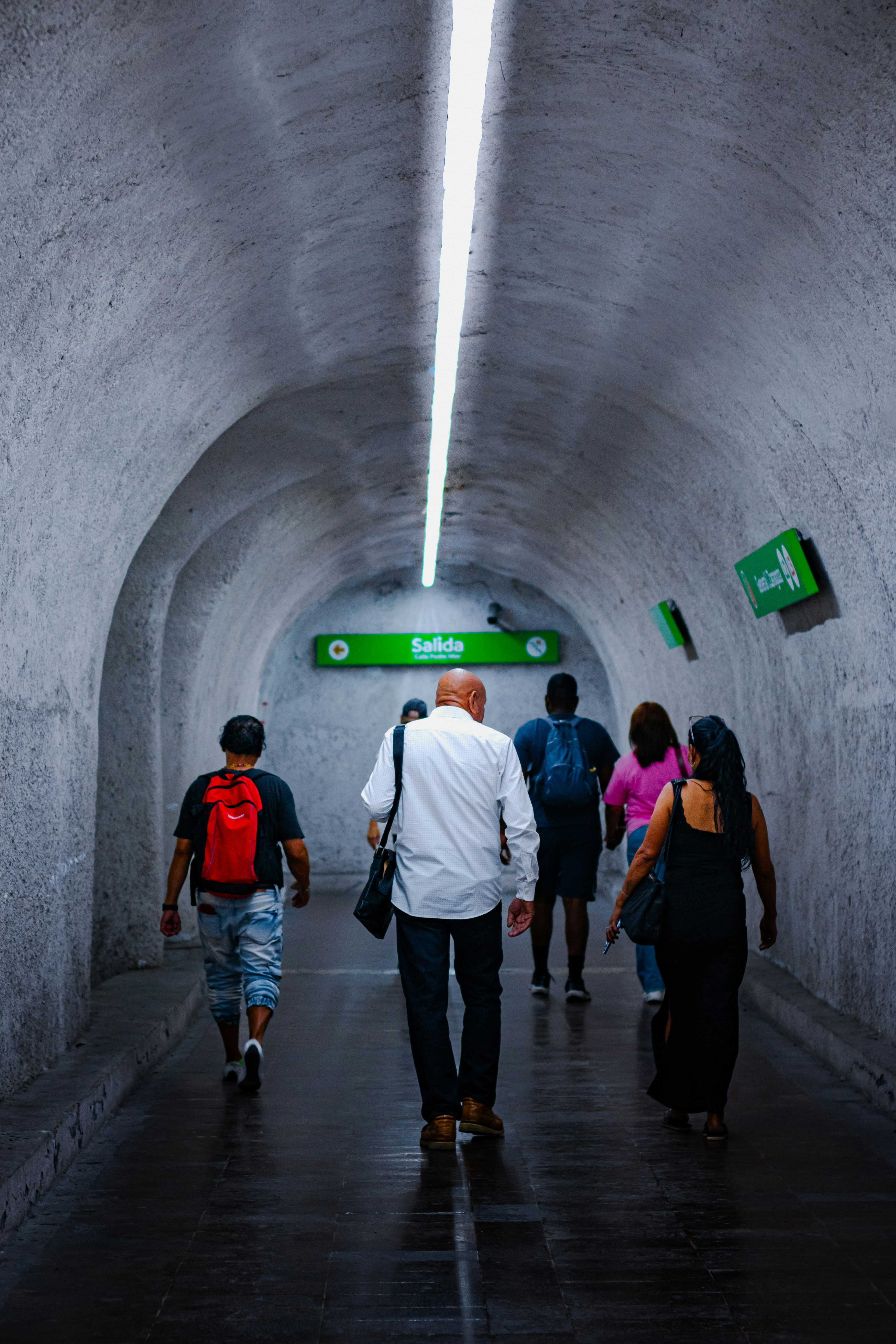 People walk through a brightly lit subway tunnel.