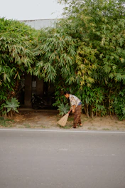 Woman sweeping near a bamboo wall