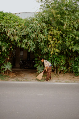 Woman sweeping near a bamboo wall