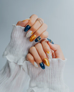 Woman's hands with ornate navy, gold, and white nails