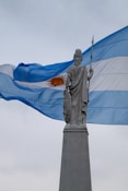 Statue in front of the waving argentinian flag