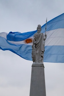 Statue in front of the waving argentinian flag