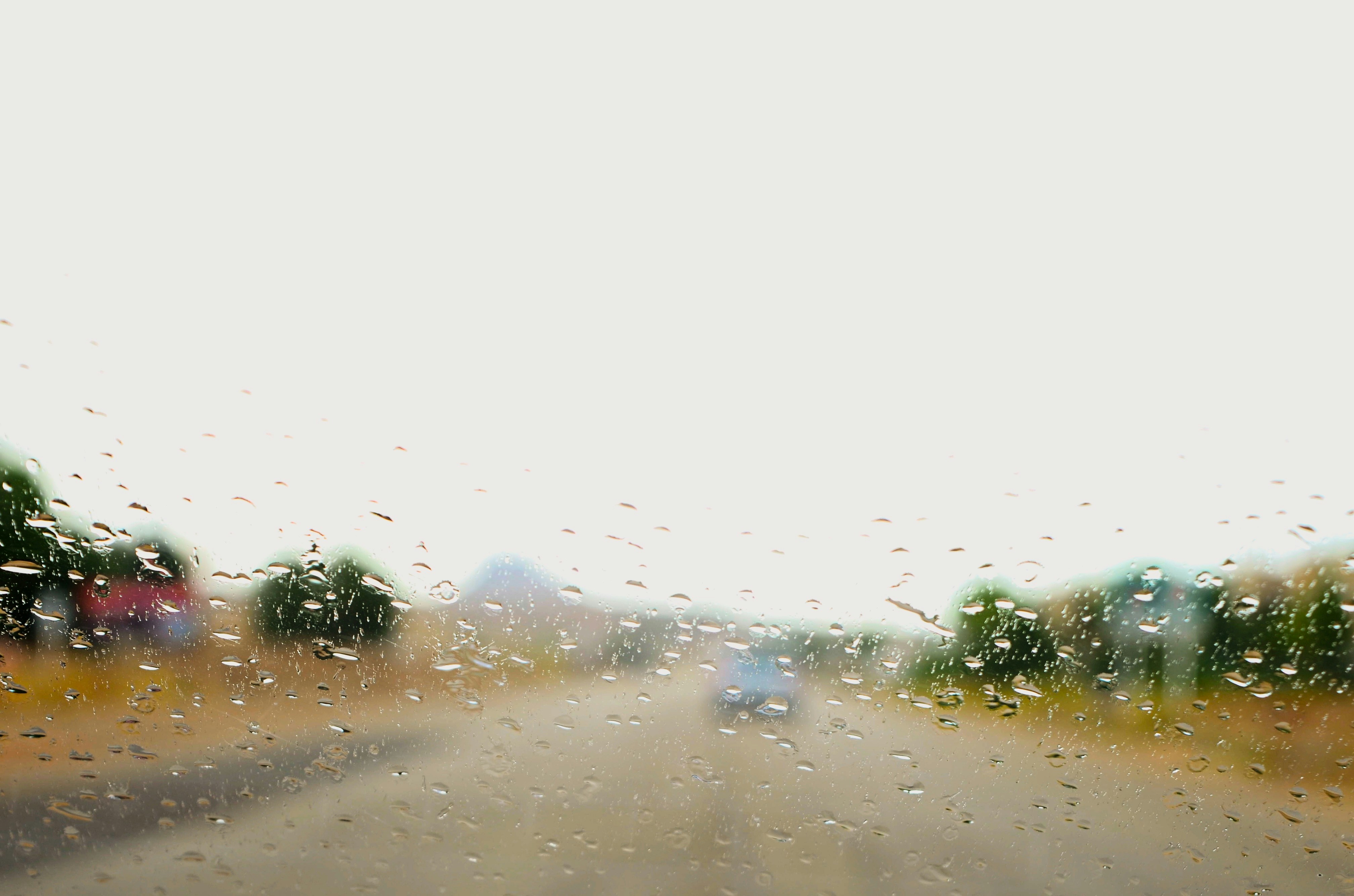 Car driving on a dusty road through a dry landscape.