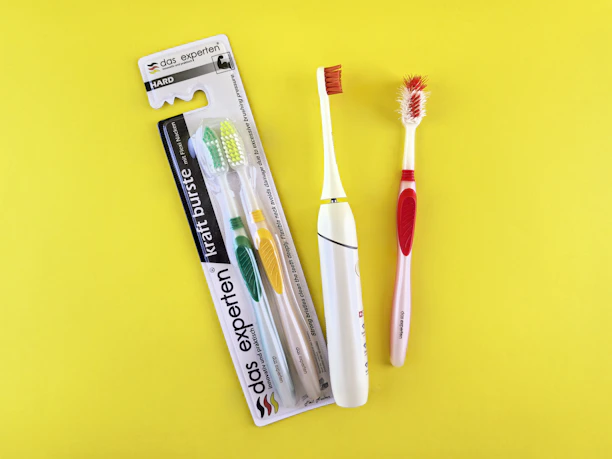Two toothbrushes and packaging on yellow background