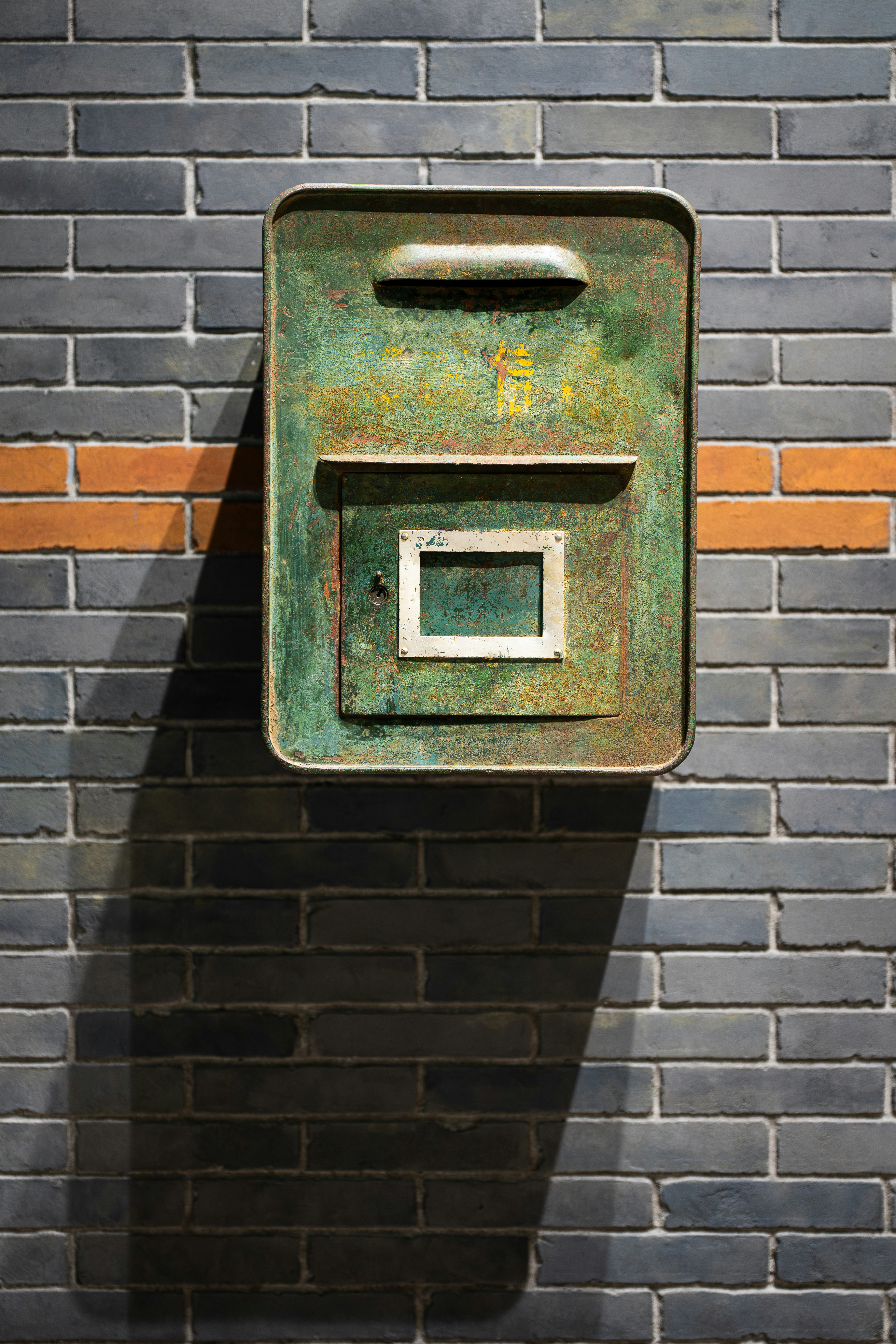 Green mailbox mounted on a brick wall