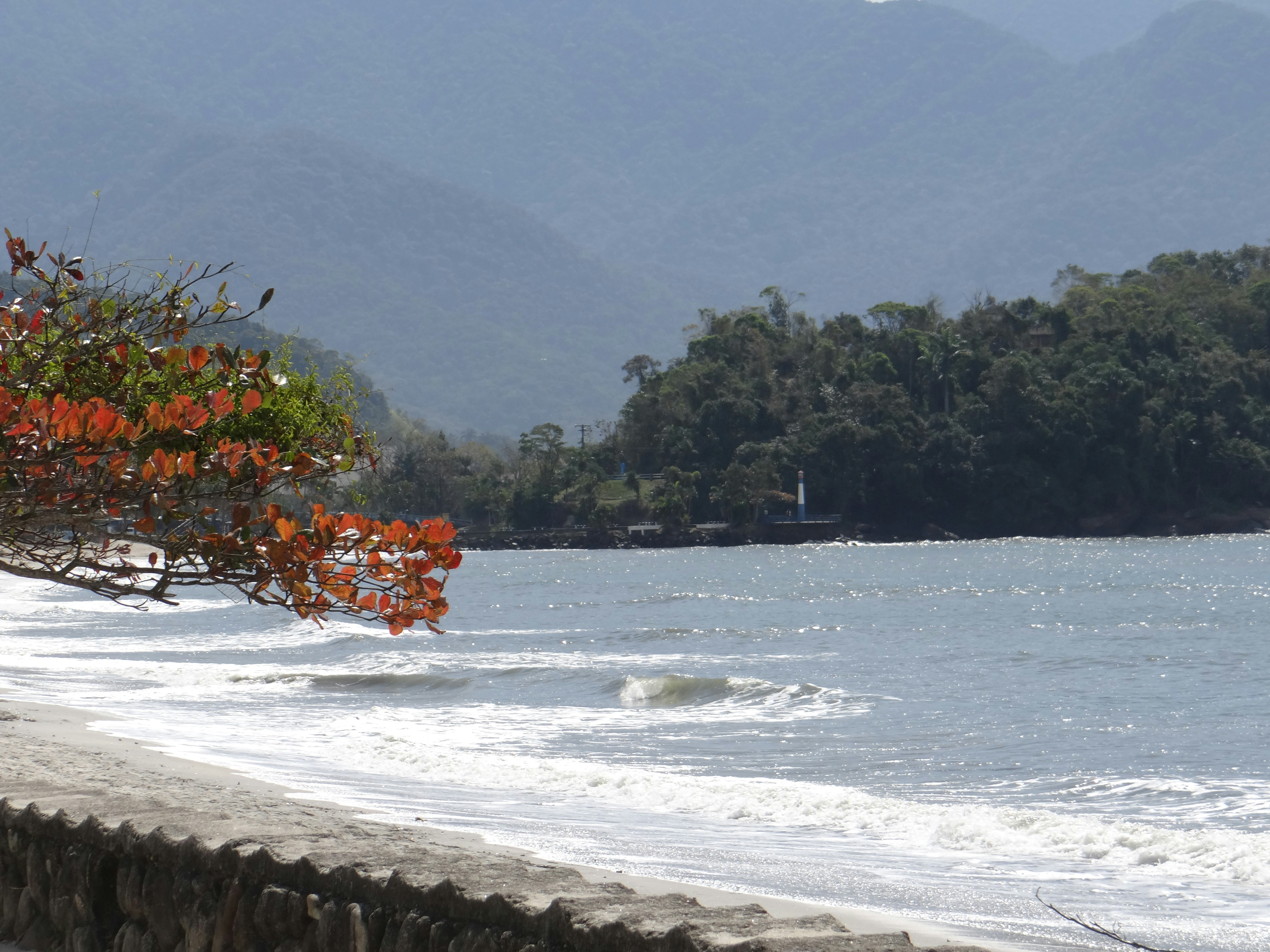 Beach with calm ocean and distant green hills.