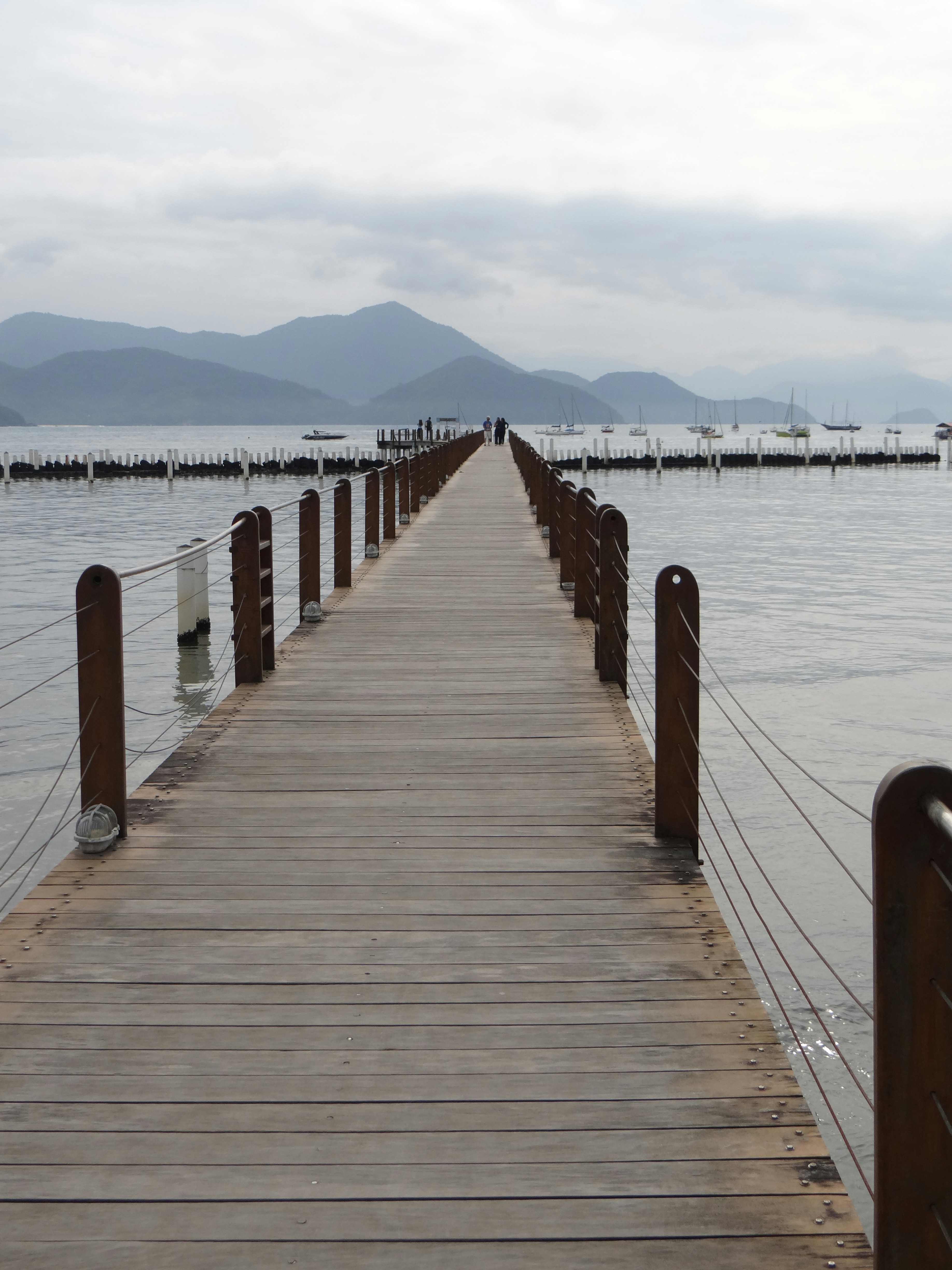 Wooden pier extending over calm water towards mountains