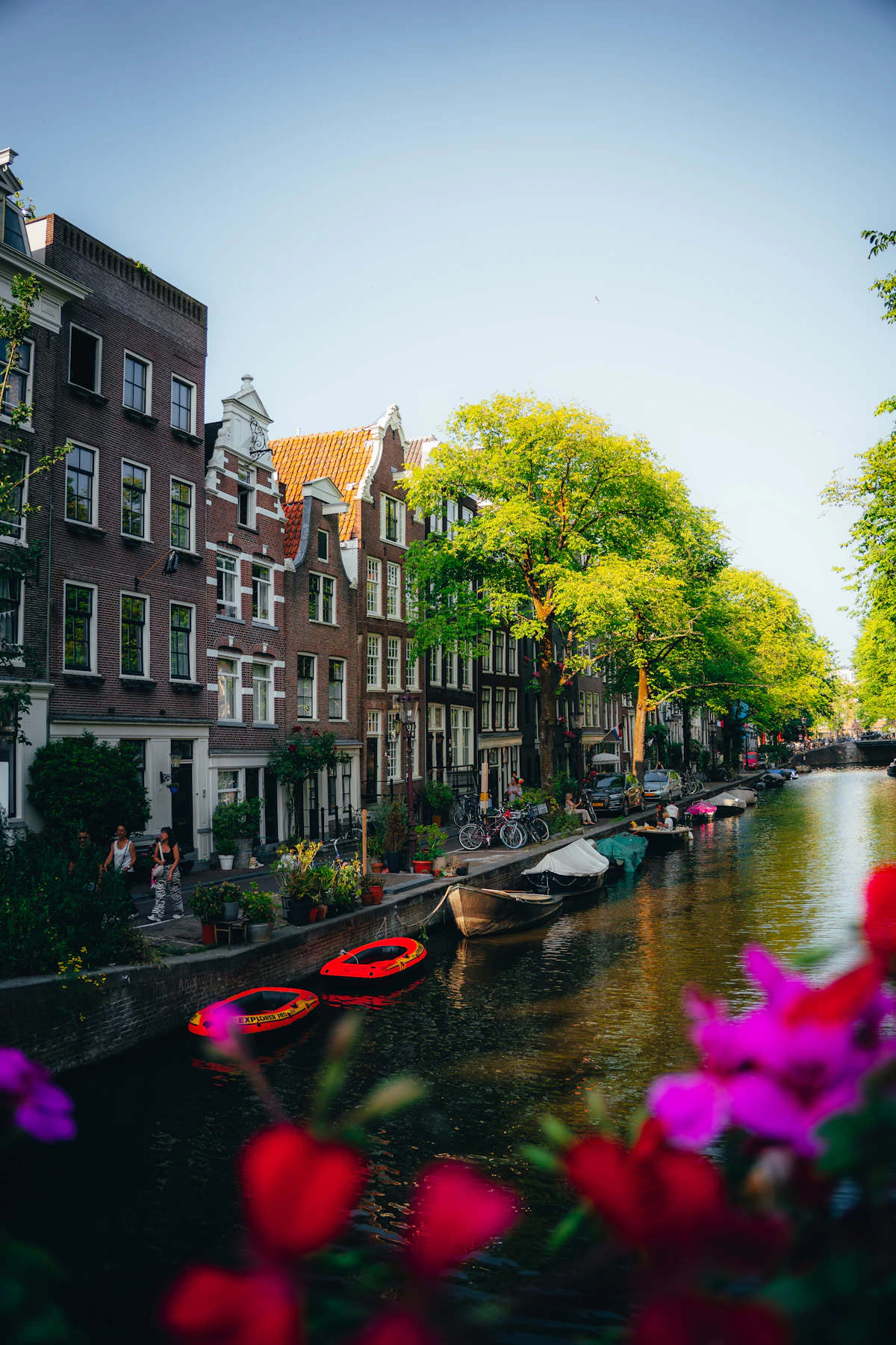Amsterdam canal houses, boats, flowers and bicycles on a bright summer day