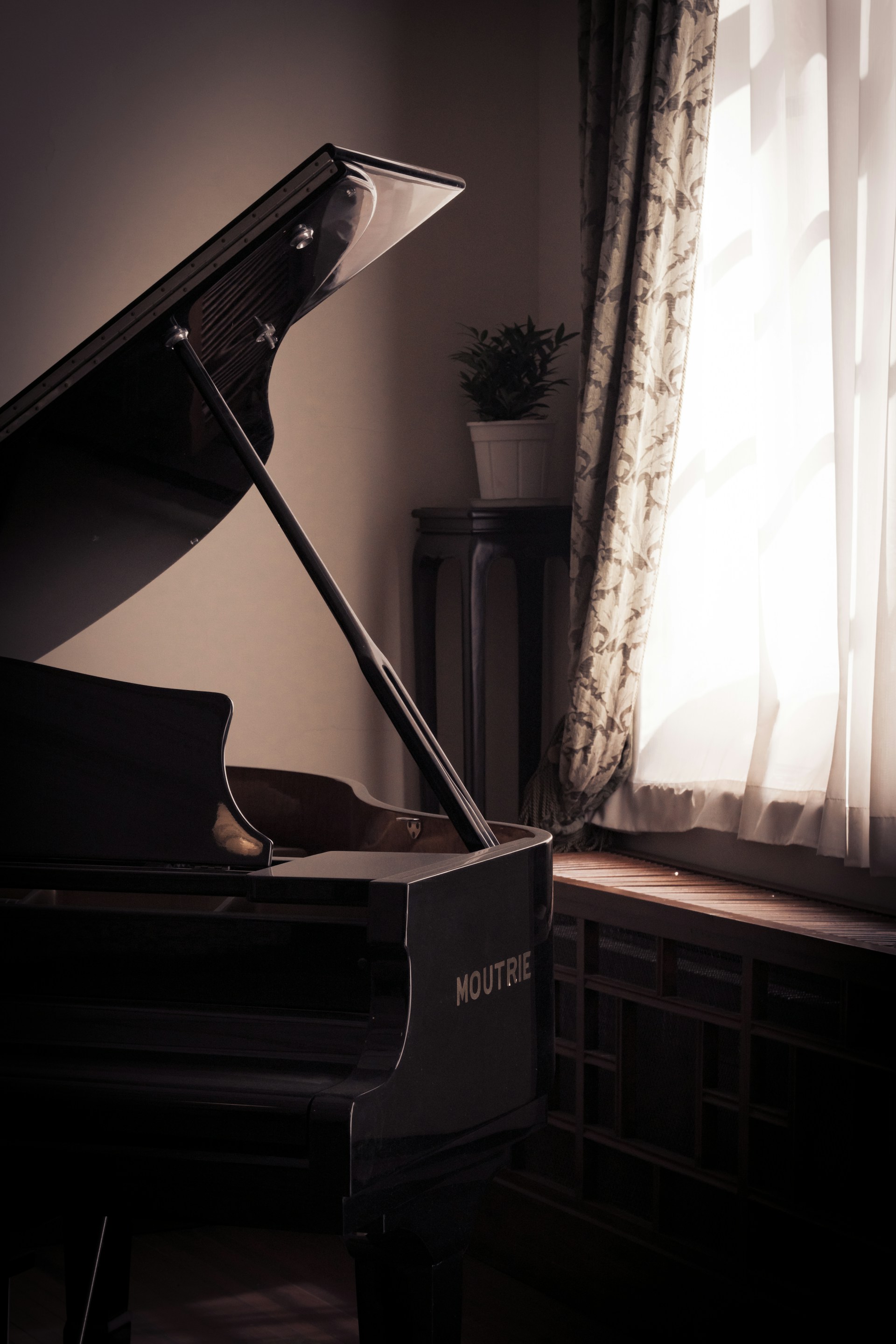 Grand piano with open lid near window