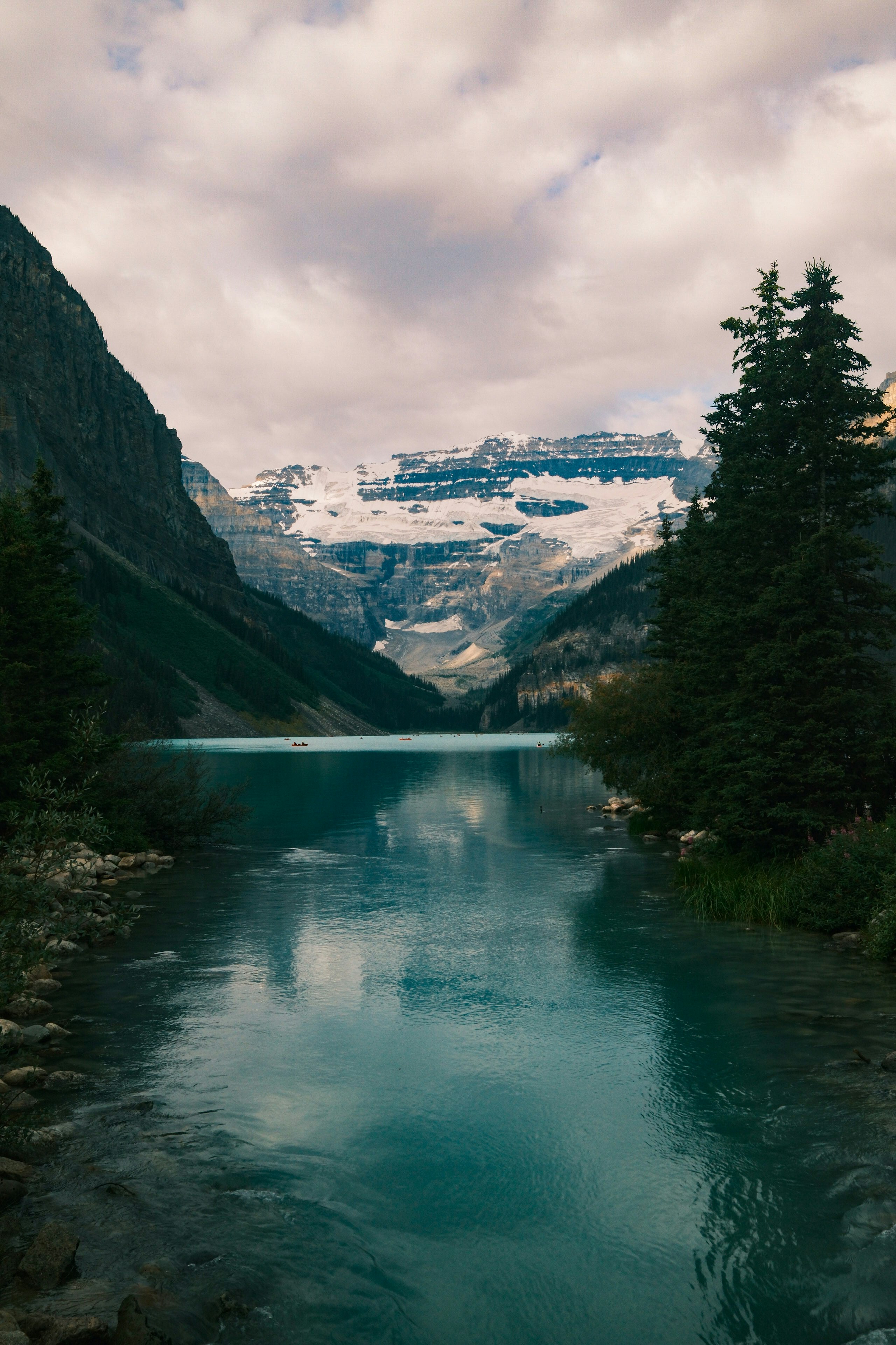 Turquoise lake reflects snow-capped mountains and cloudy sky
