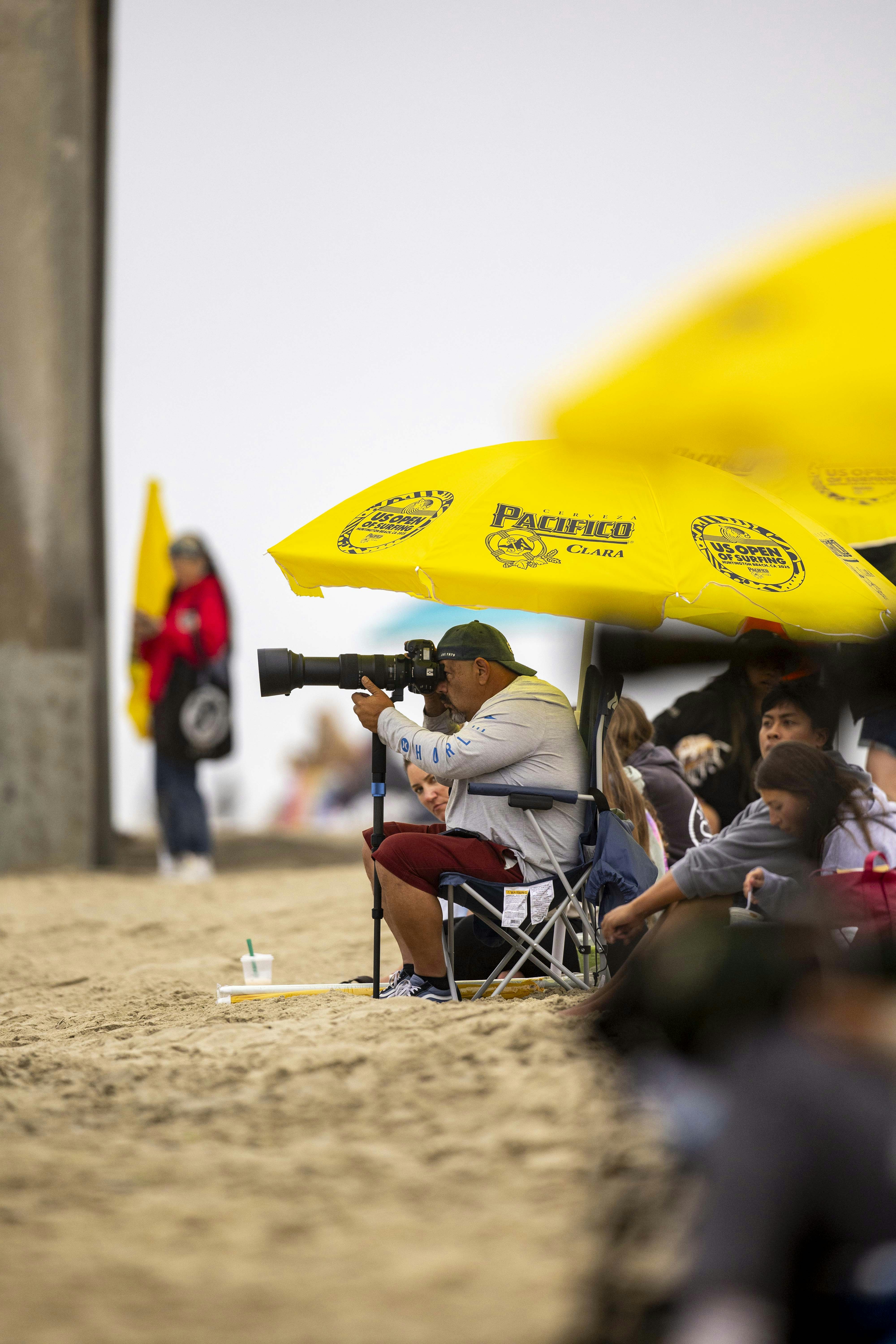 Photographe avec grand objectif sur la plage de sable sous parasol