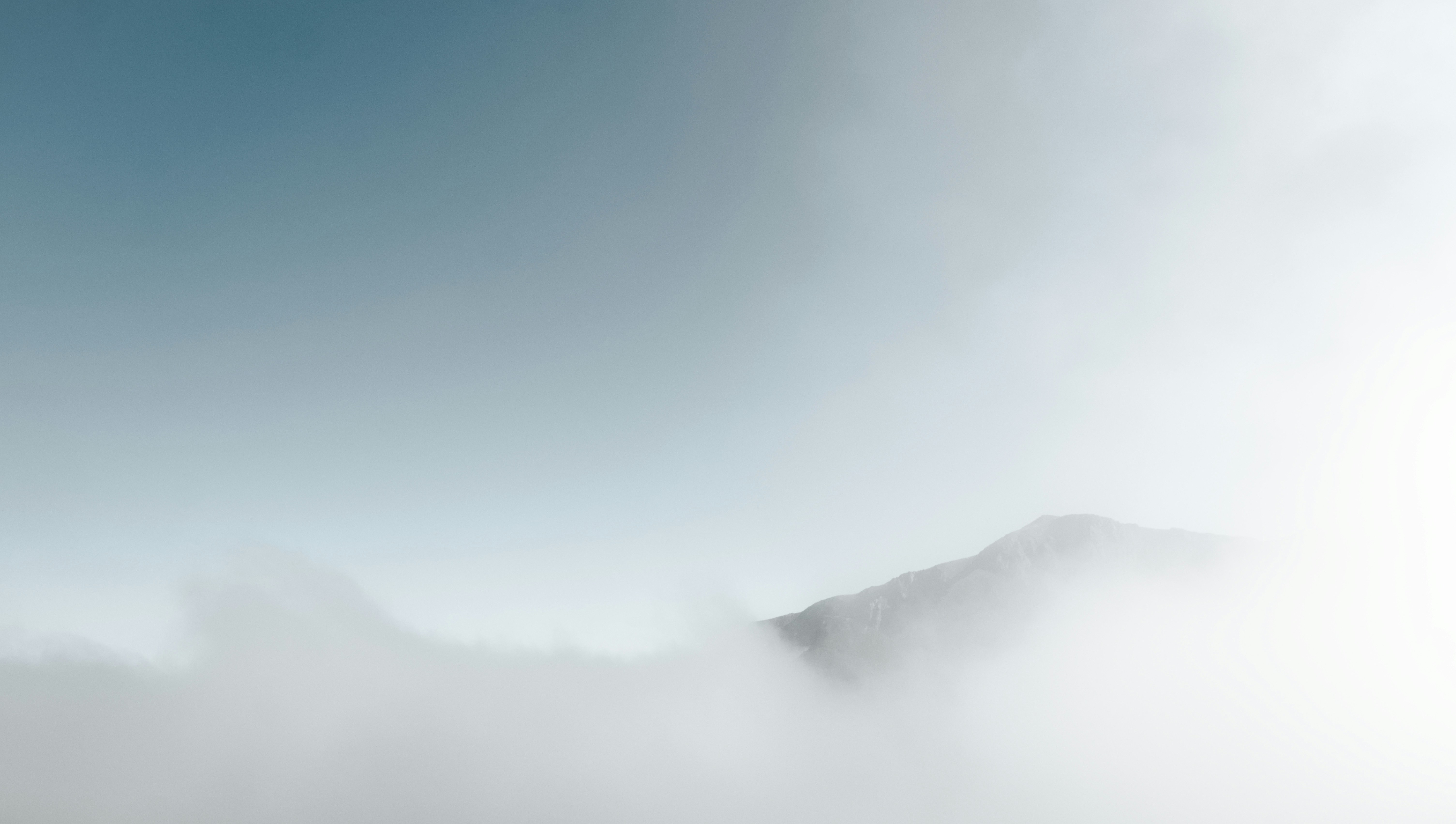 Mountain peak emerging from soft clouds at dawn