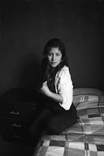 Woman sitting on a bed with dark background