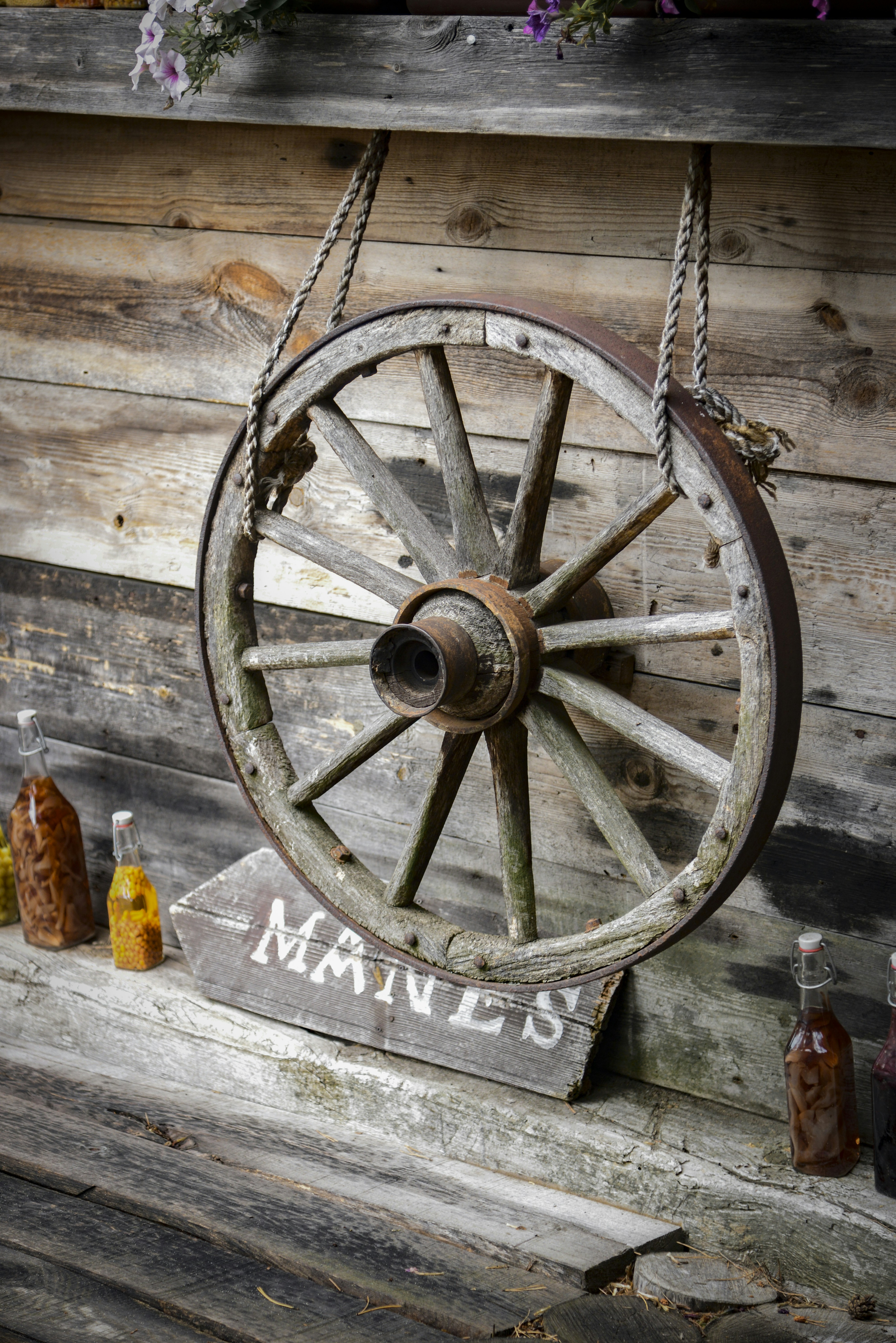 Rustic wooden wagon wheel hanging on a wall.