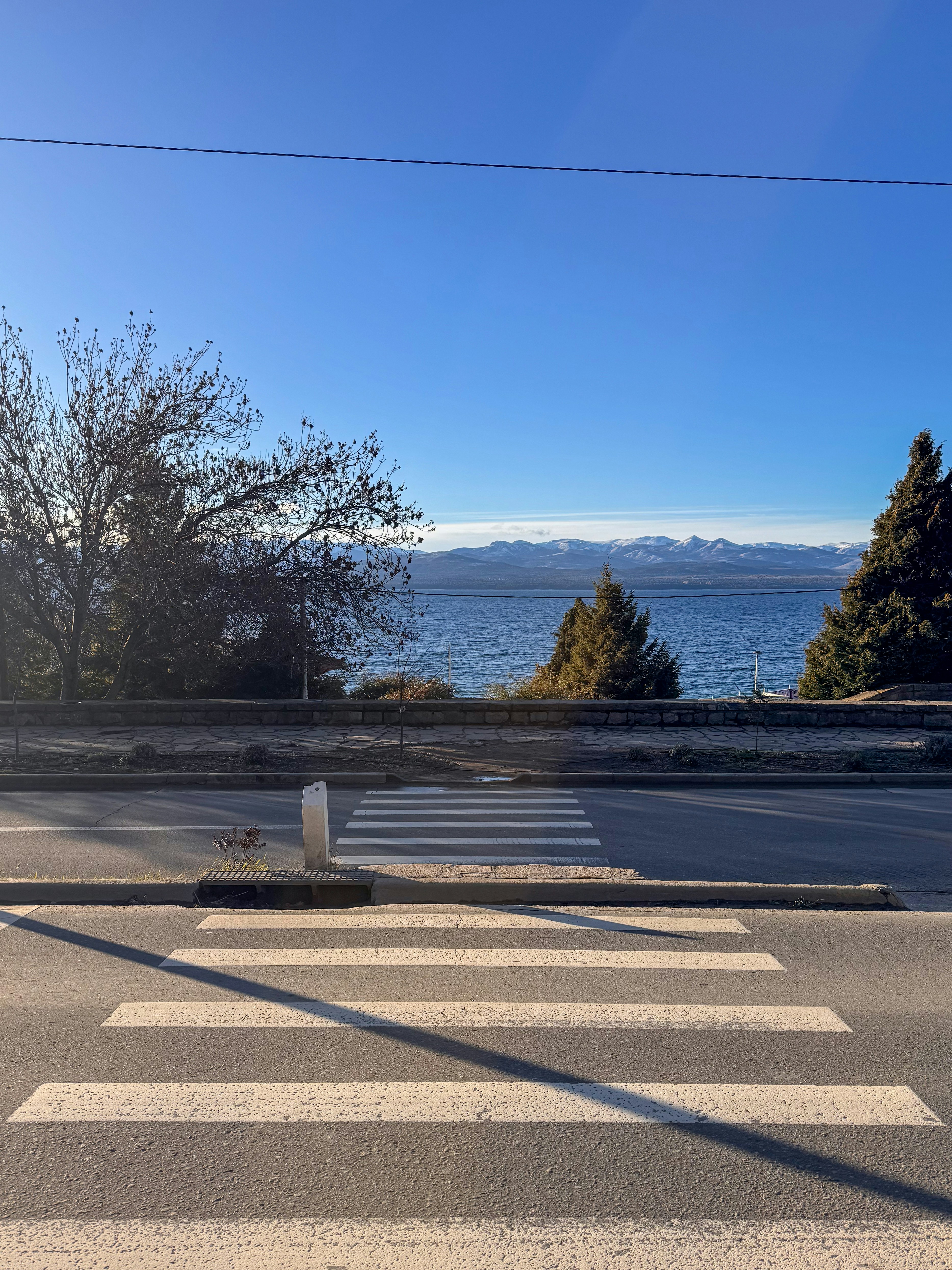 Crosswalk on road with distant lake and mountains