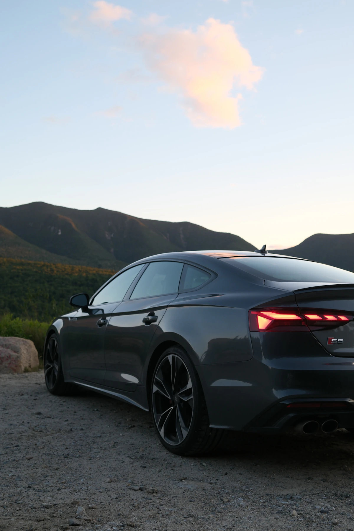 Dark gray sedan overlooking forested mountains