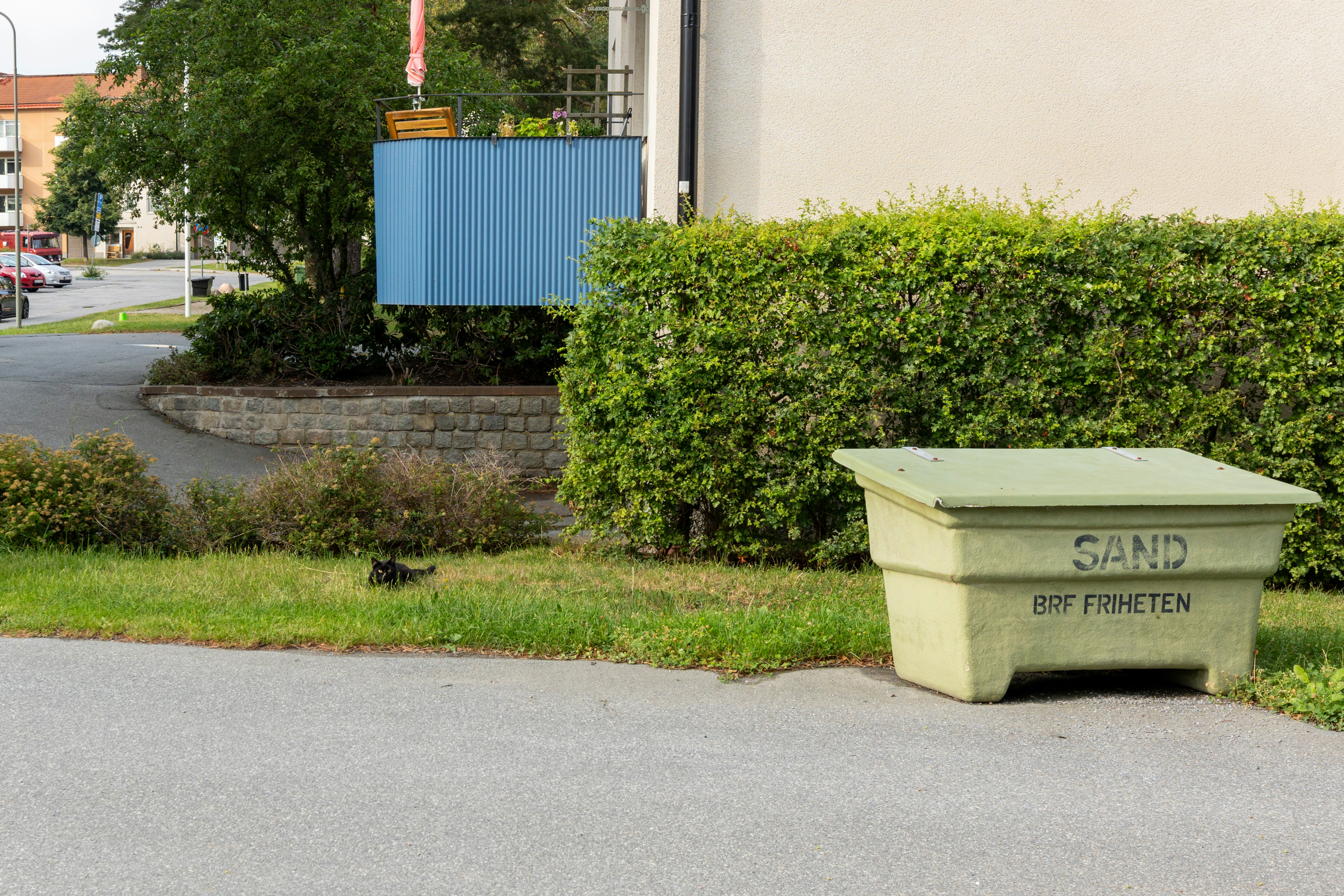 A light green beehive sits on a paved surface.