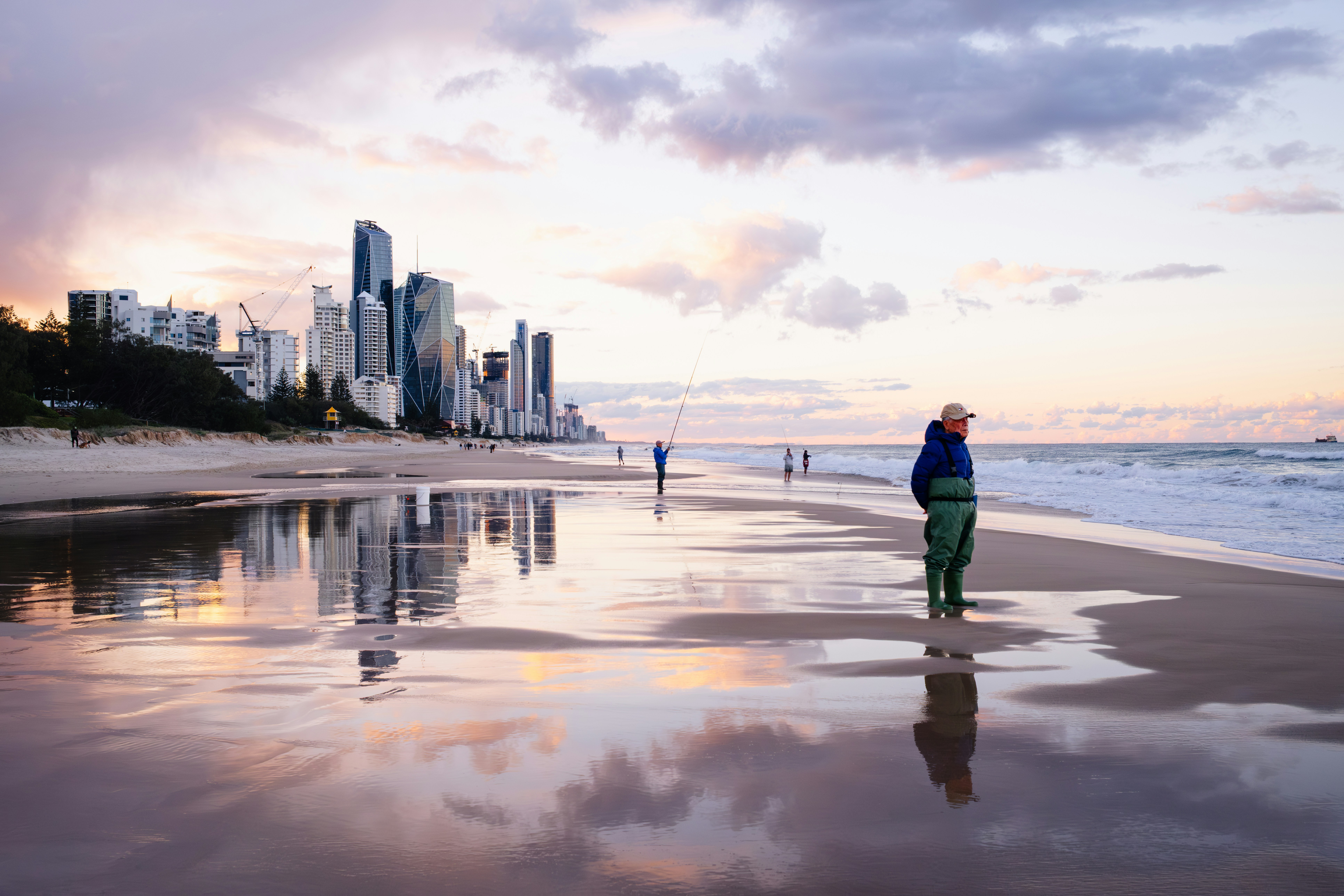 Person on beach with city skyline at sunset