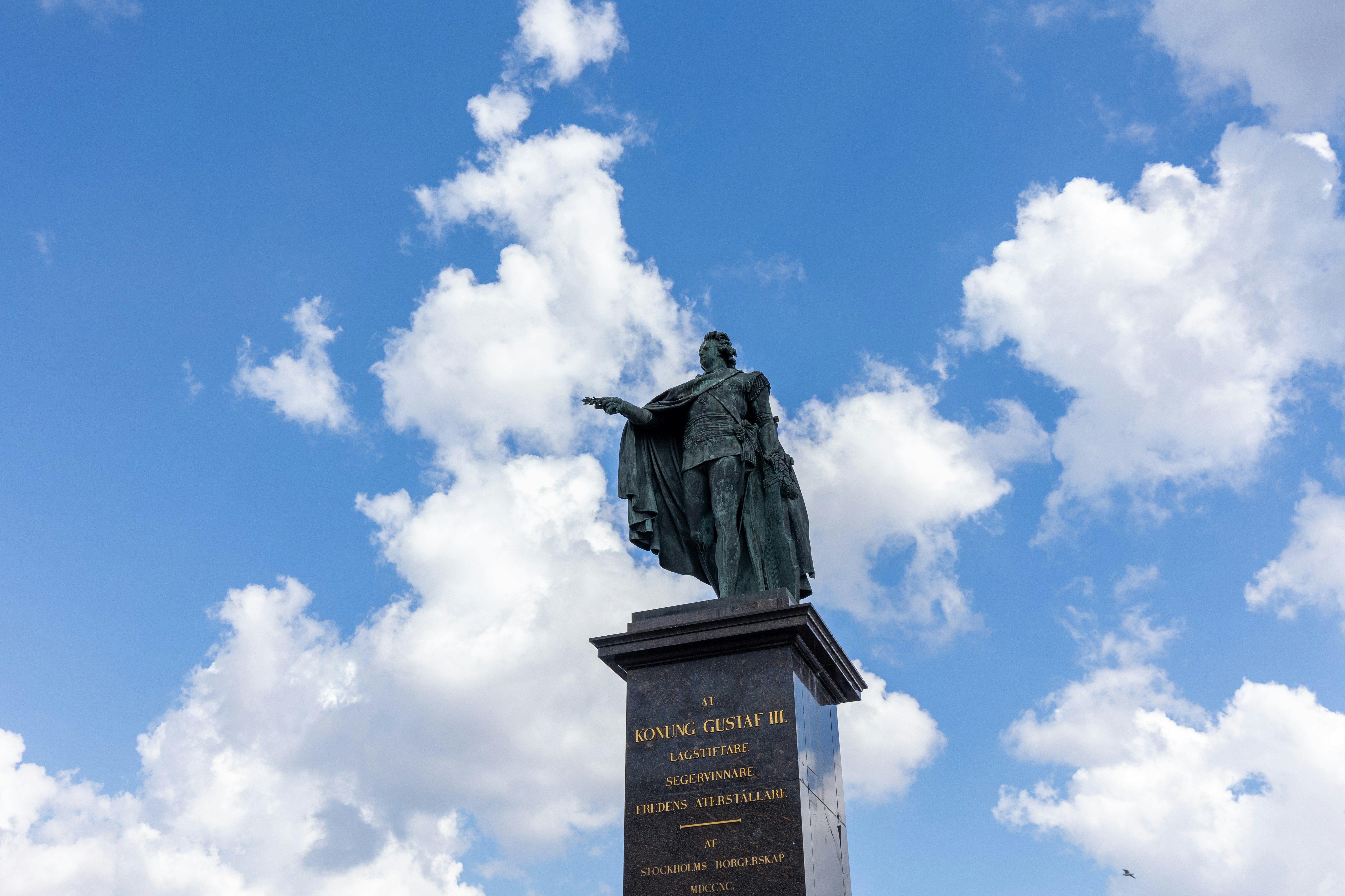 Statue against a bright blue sky with clouds
