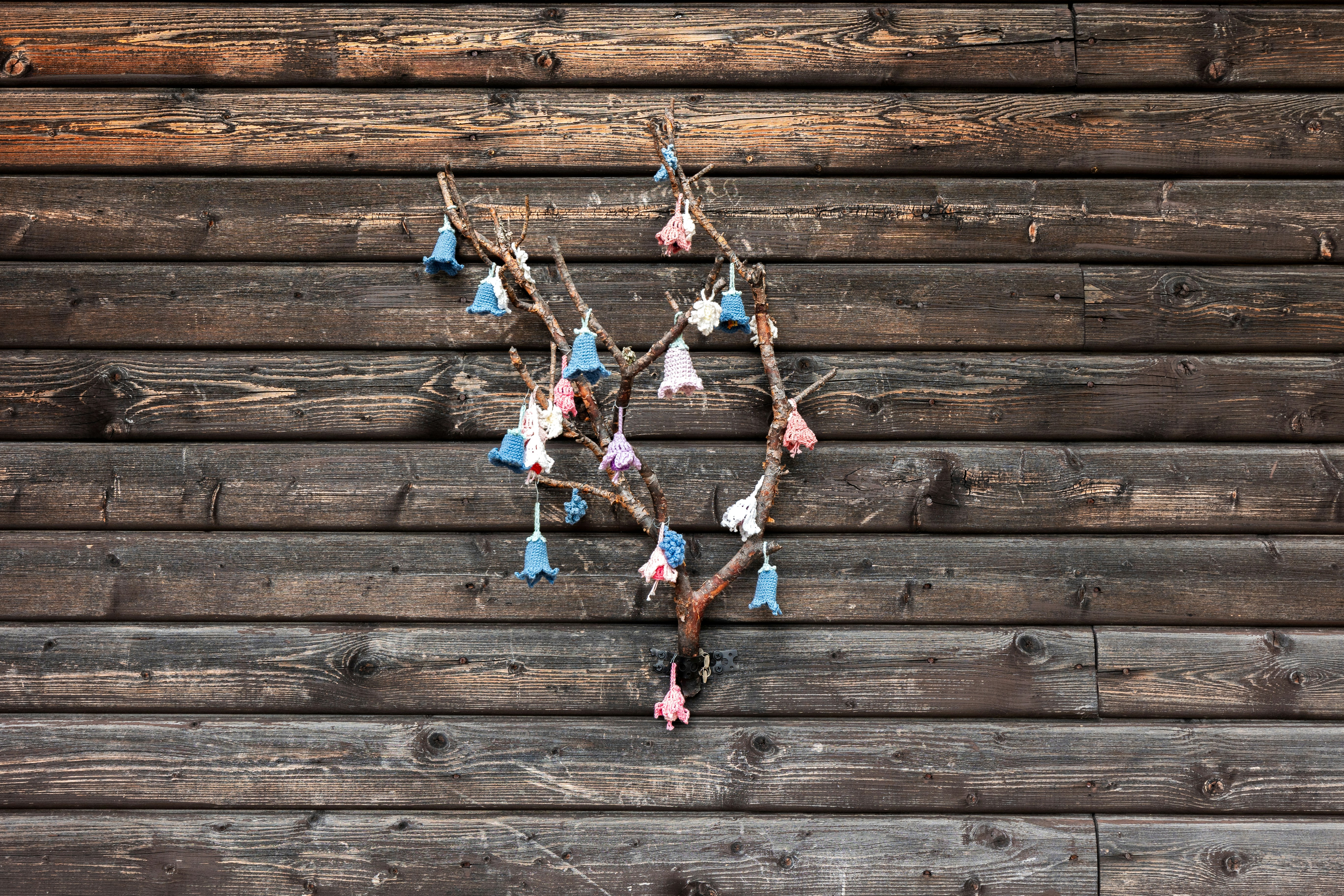 A delicate wind chime hangs on a wooden wall.