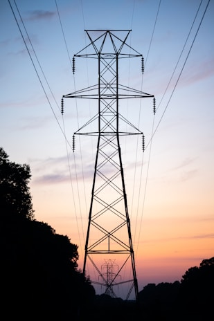 Tall power line tower against a sunset sky