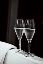 Two glasses of champagne on a white surface