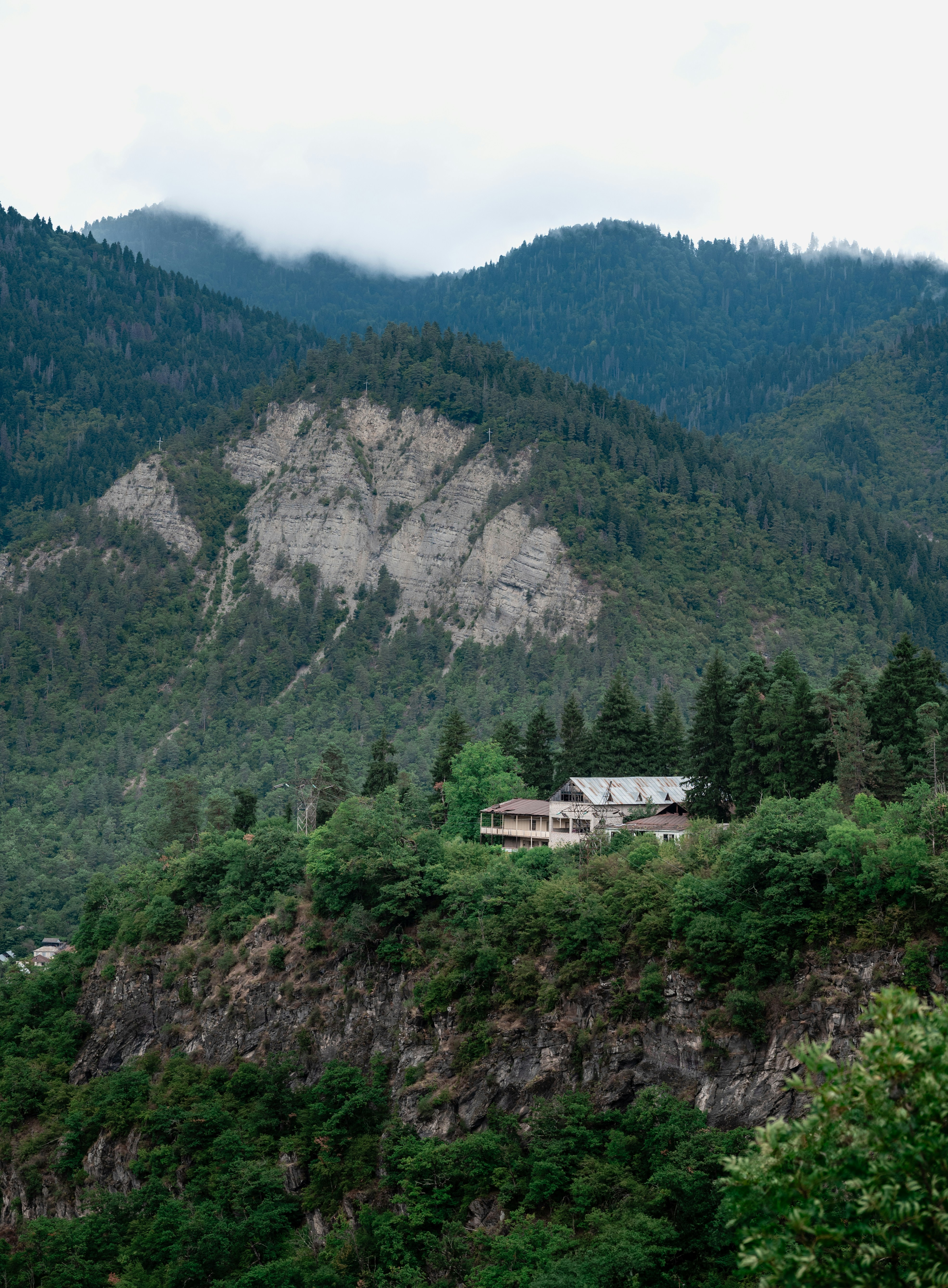 Green forested mountains with a building on a hill.