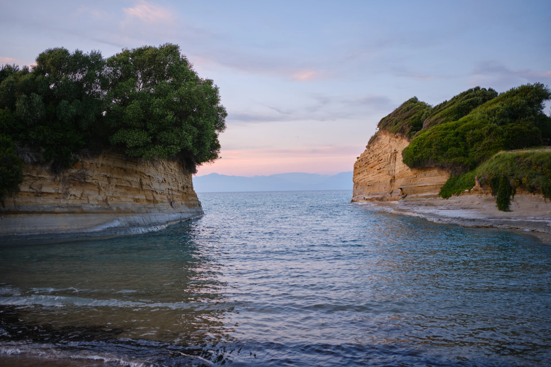 Calm sea between two rocky shores at sunset