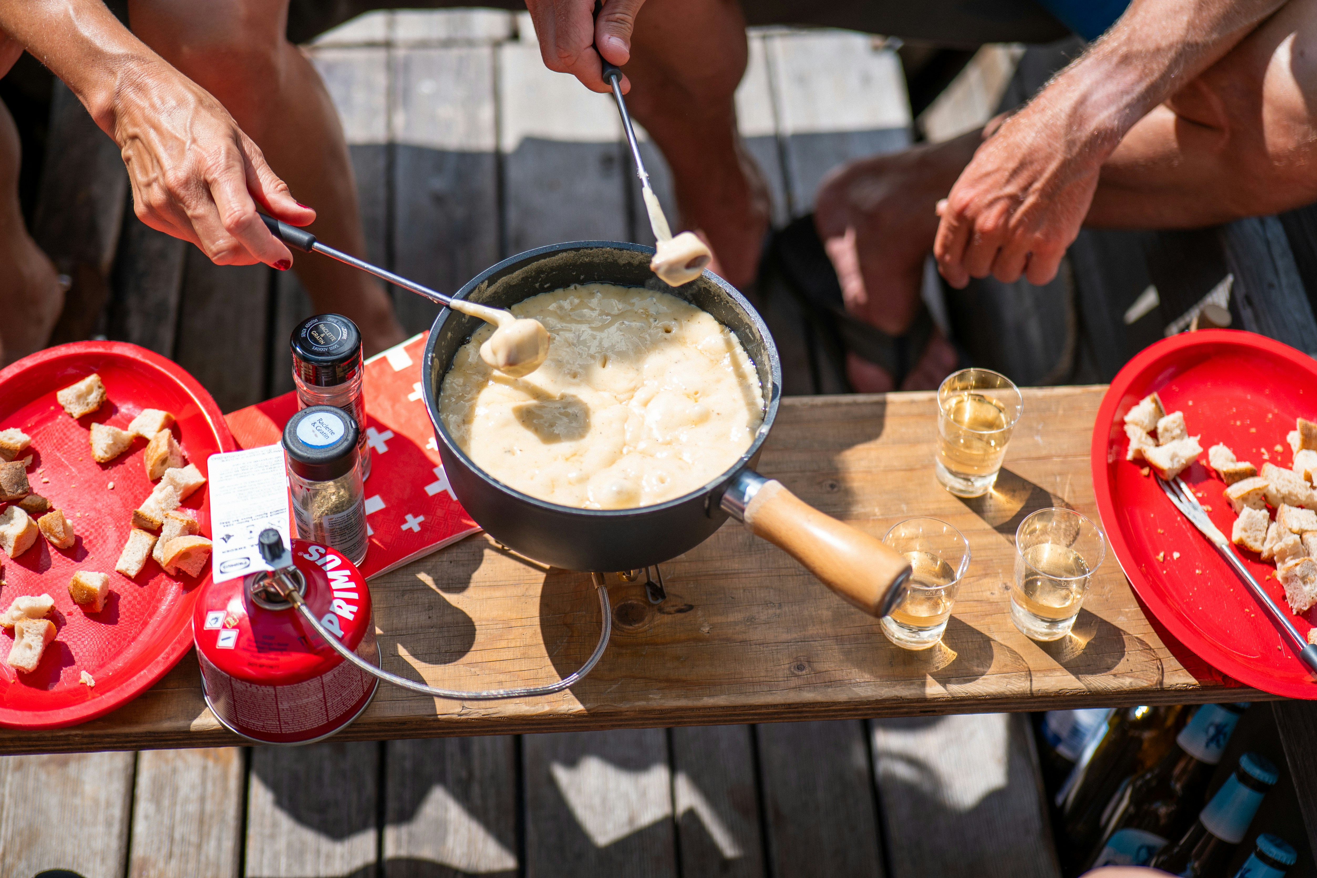 People dipping bread into a cheese fondue pot.