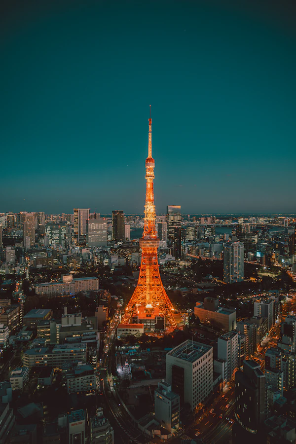 Orange-lit Tokyo Tower among city buildings at dusk.