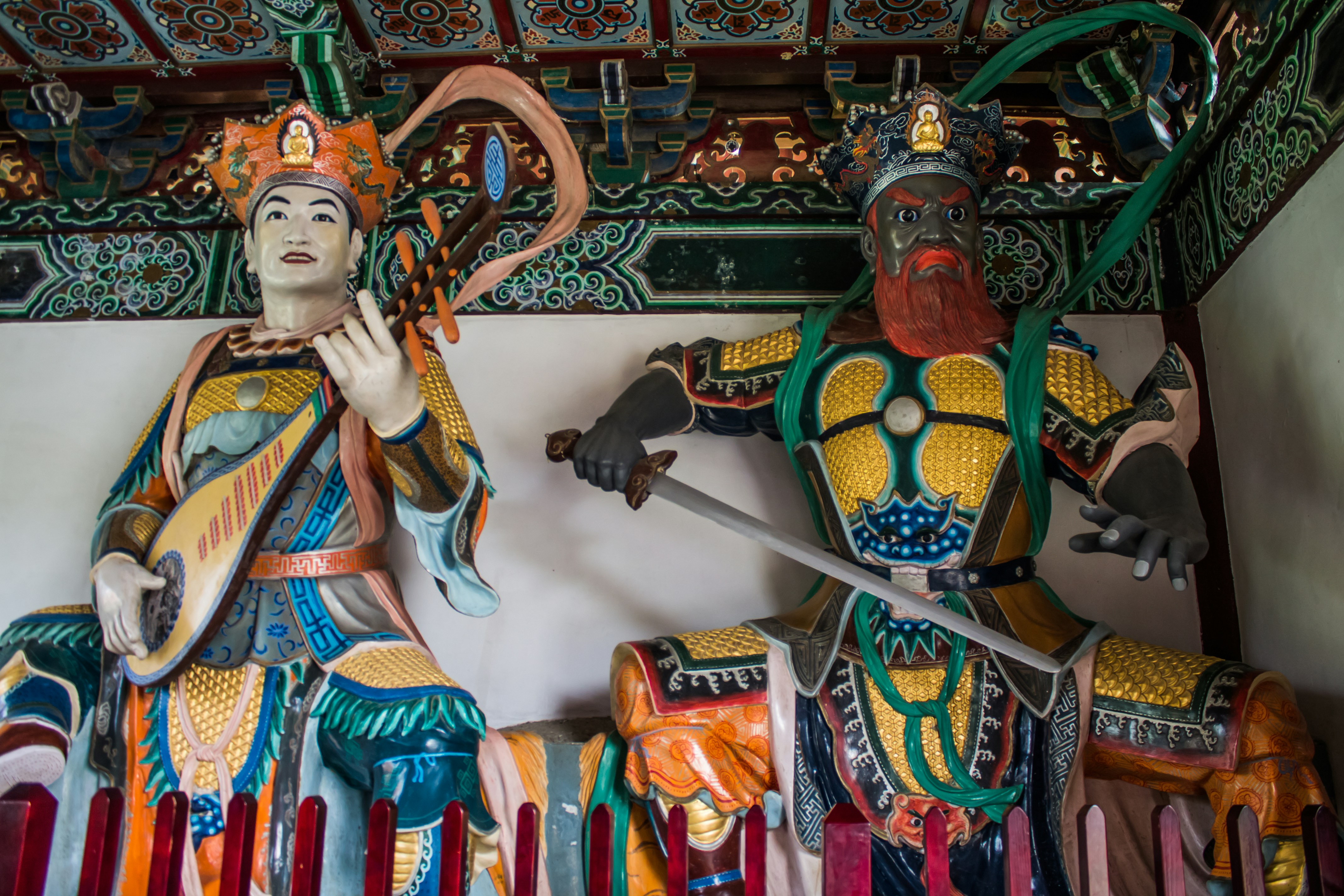 Two colorful statues of warriors with weapons.