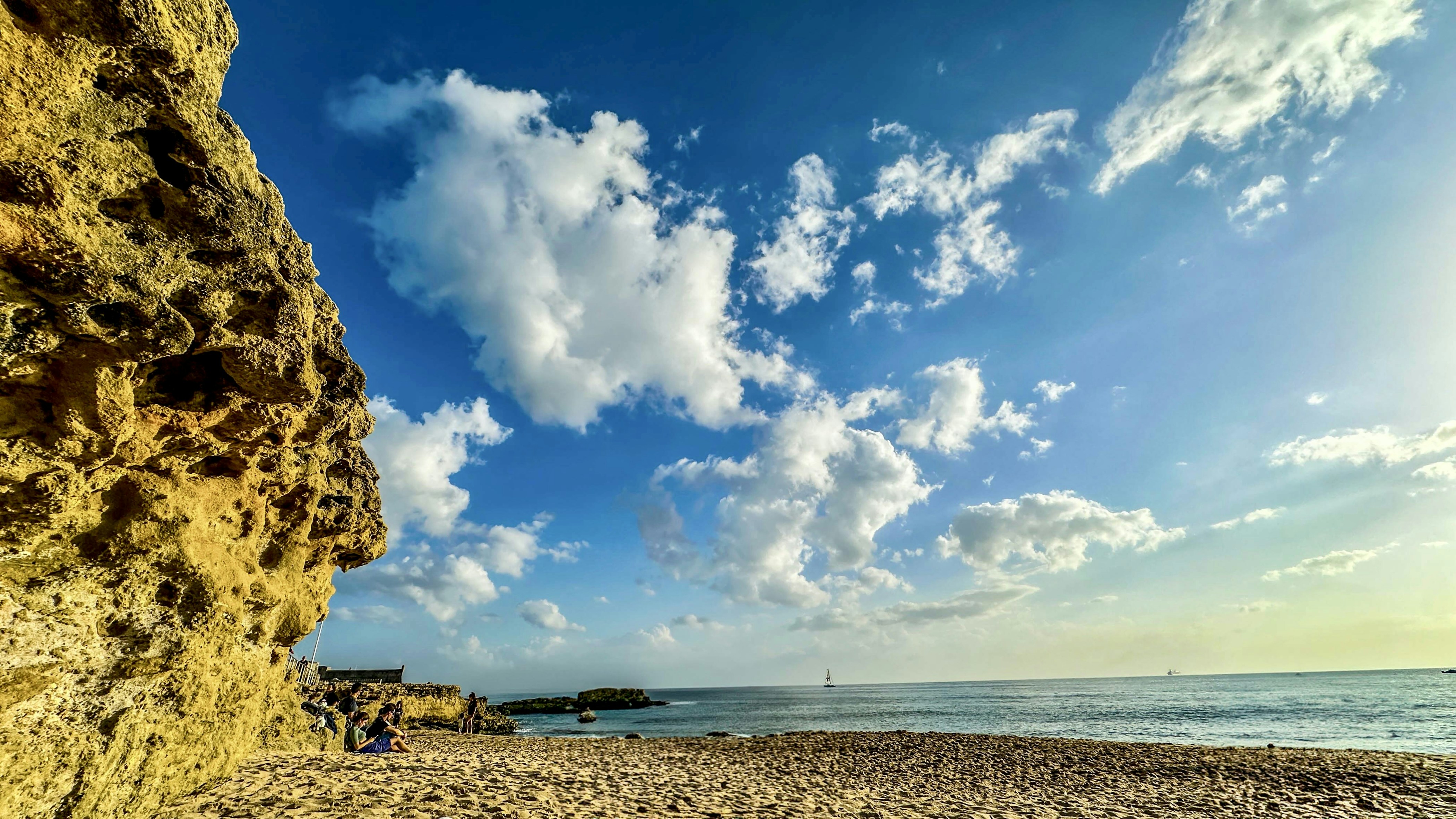 바위 절벽과 푸른 하늘이 있는 모래 해변