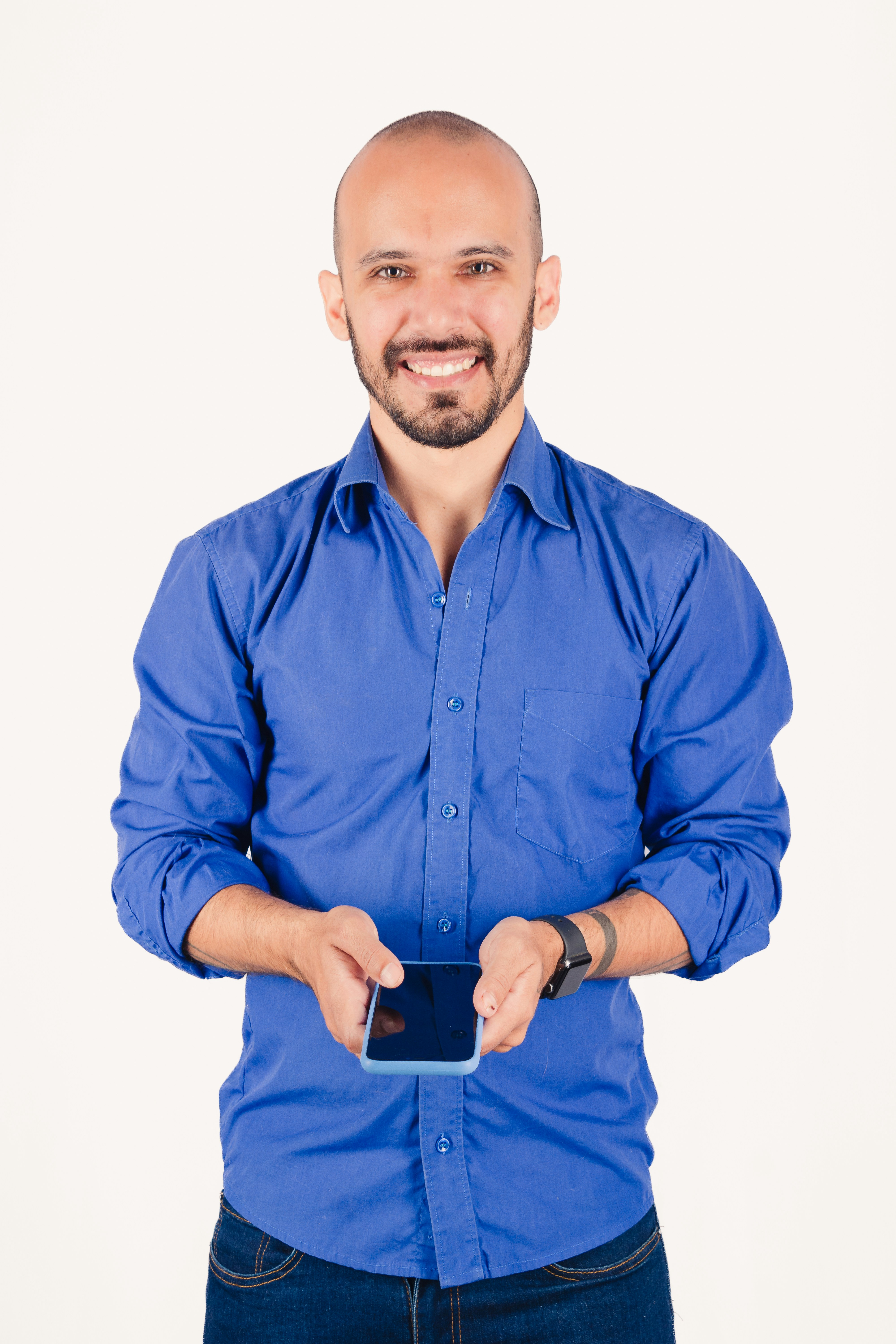 Homme chauve en chemise bleue tenant un smartphone