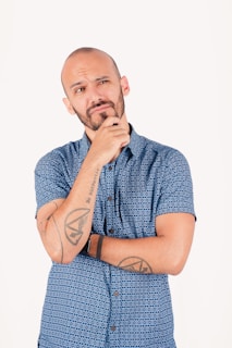 Man with beard thinking with hand on chin.