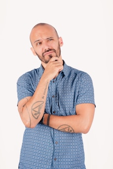 Man with beard thinking with hand on chin.