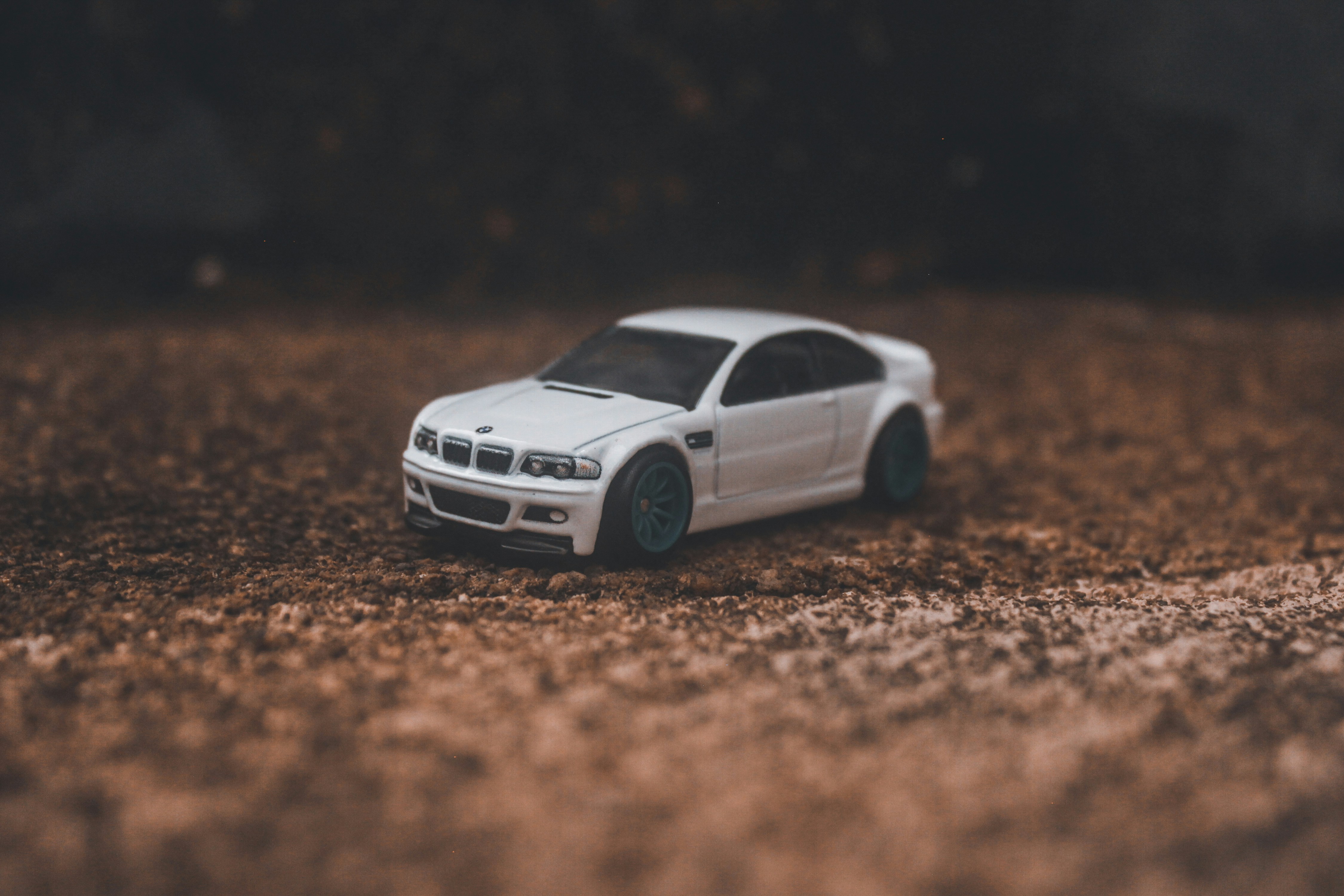A white sports car parked on a dirt road.