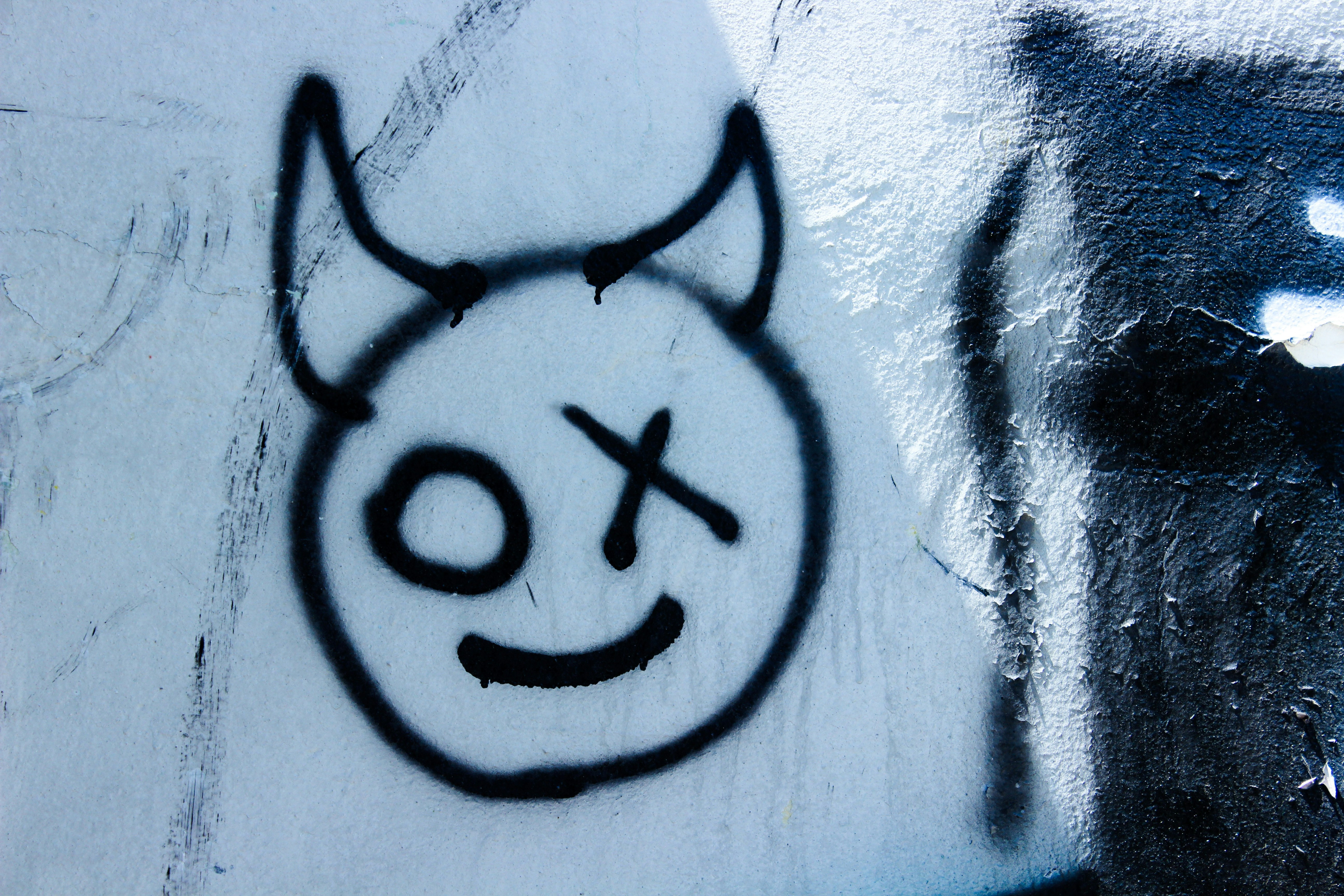 Graffiti of a devilish smiley face with one eye