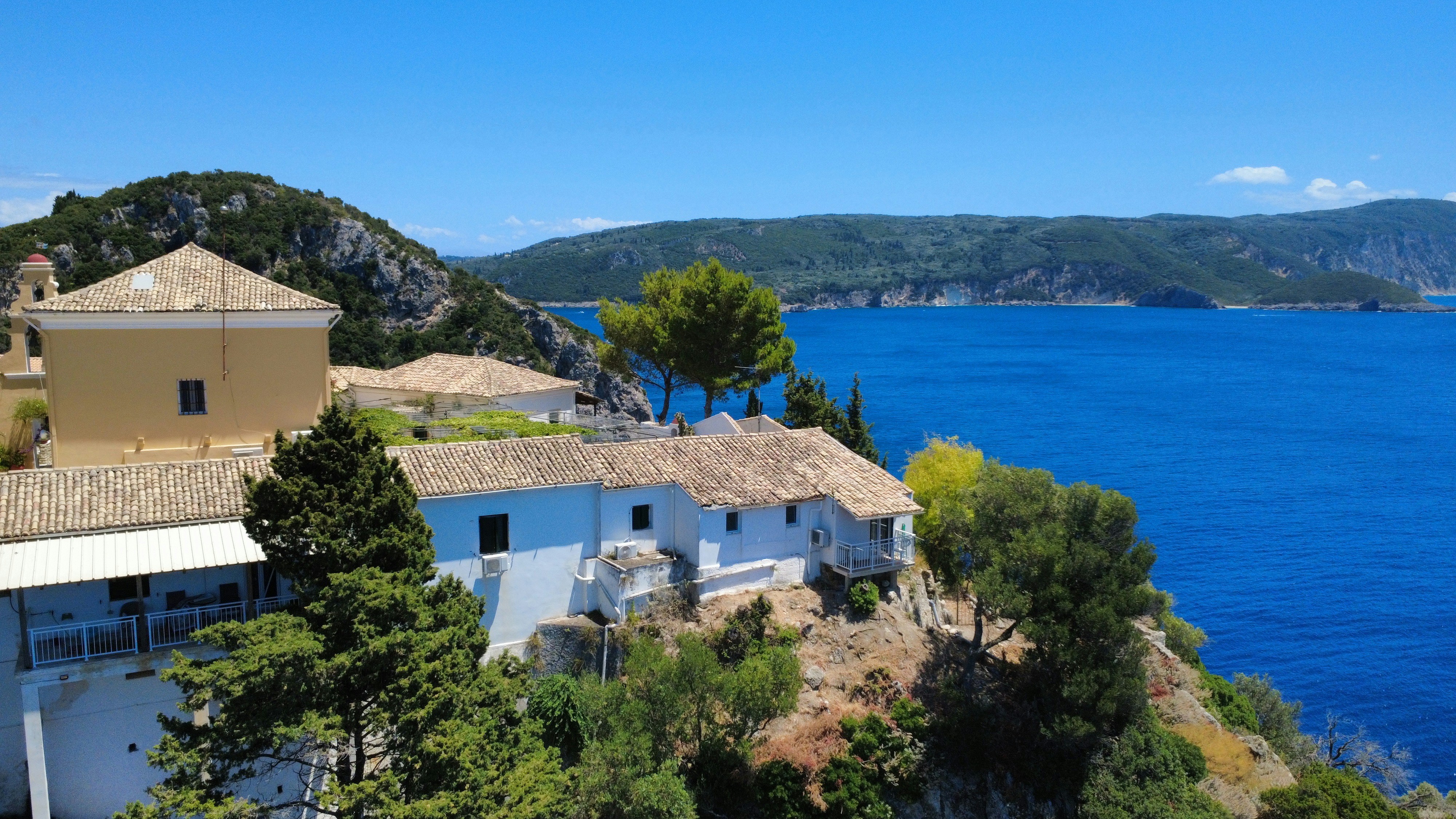 White building on a hill overlooking blue water