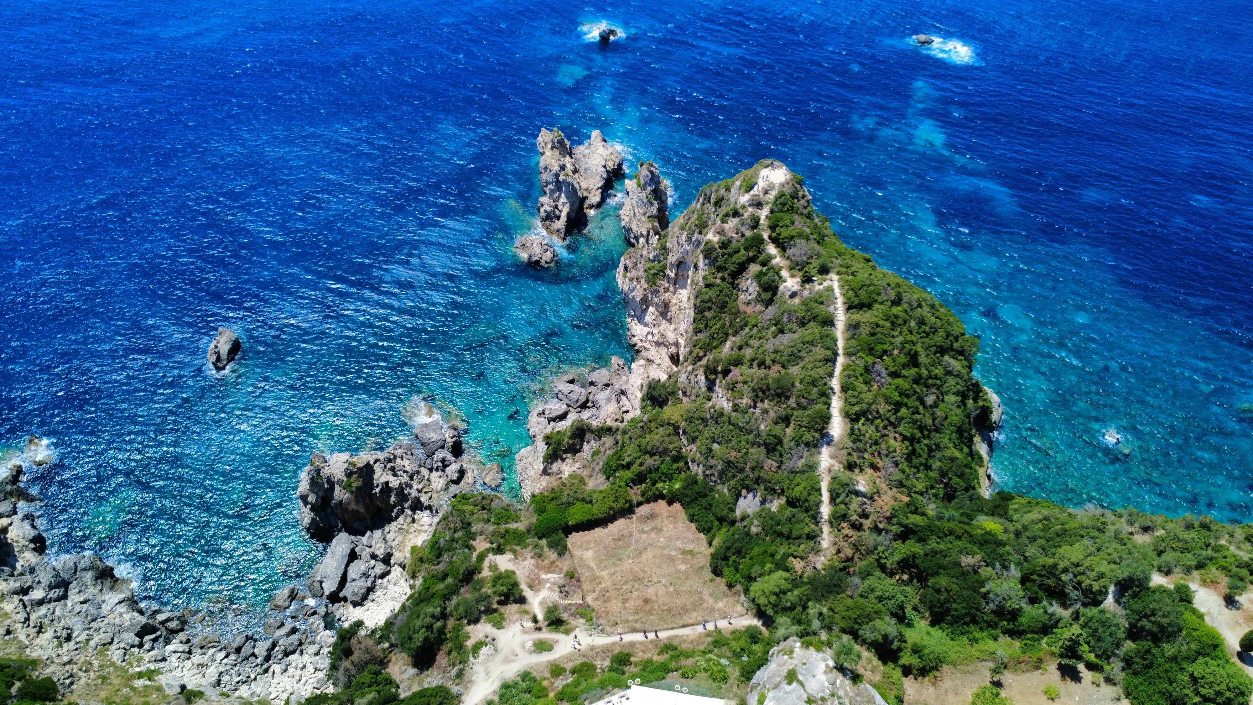 Boats sail near rocky islands in blue ocean.