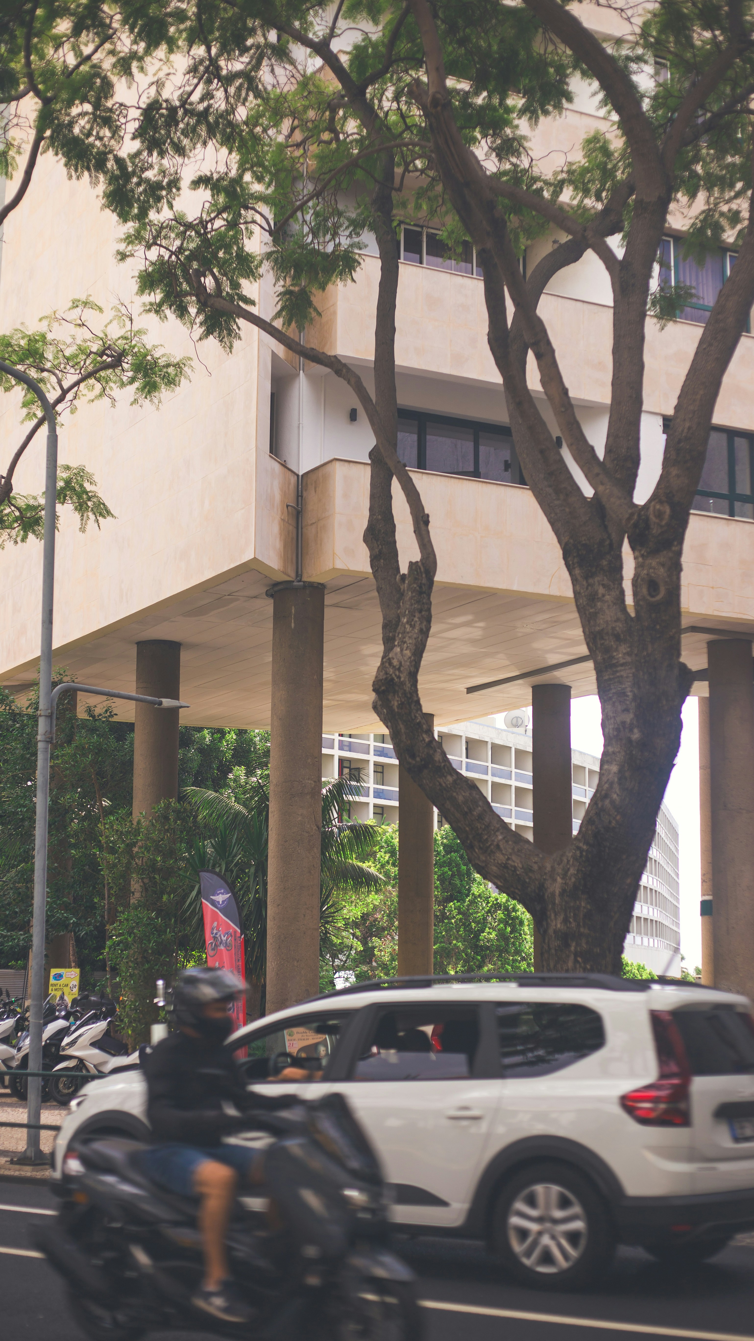 Motorcyclist and car driving on a city street.