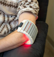 Person with red light therapy device on arm
