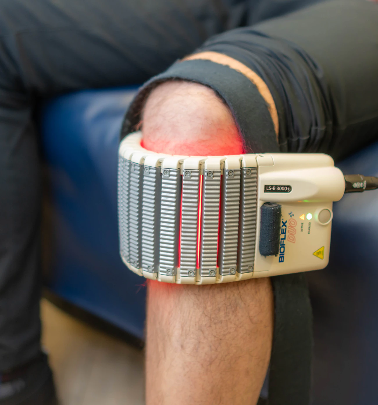 Close-up of a red light-based therapy device being applied against skin, representing the light and laser-based technology used for redness and vascular concerns