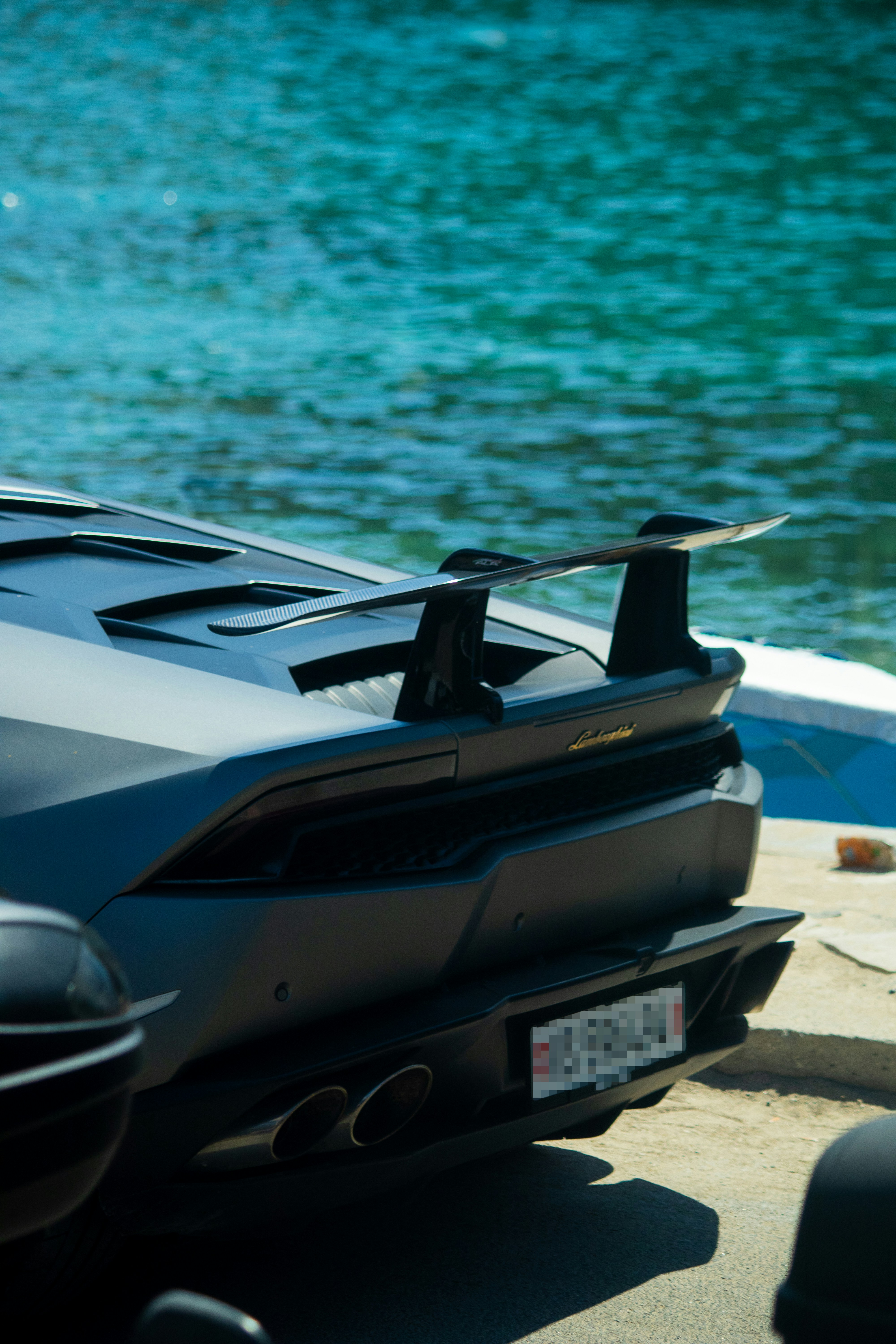 Dark sports car parked by the blue ocean water