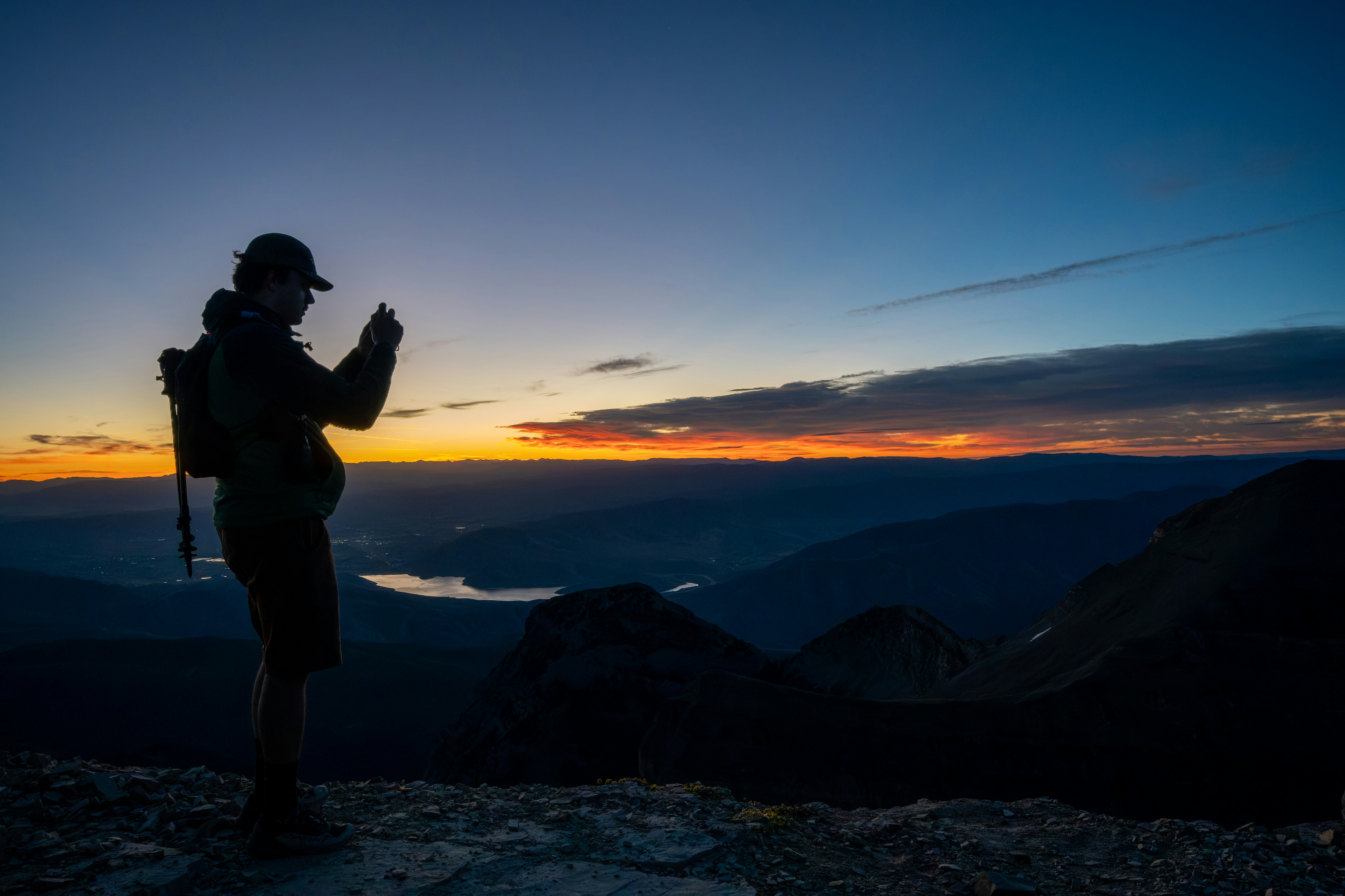 Backpacker using portable solar chargers during sunrise at a remote wilderness campsite
