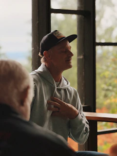 Man in baseball cap talking with hand on chest