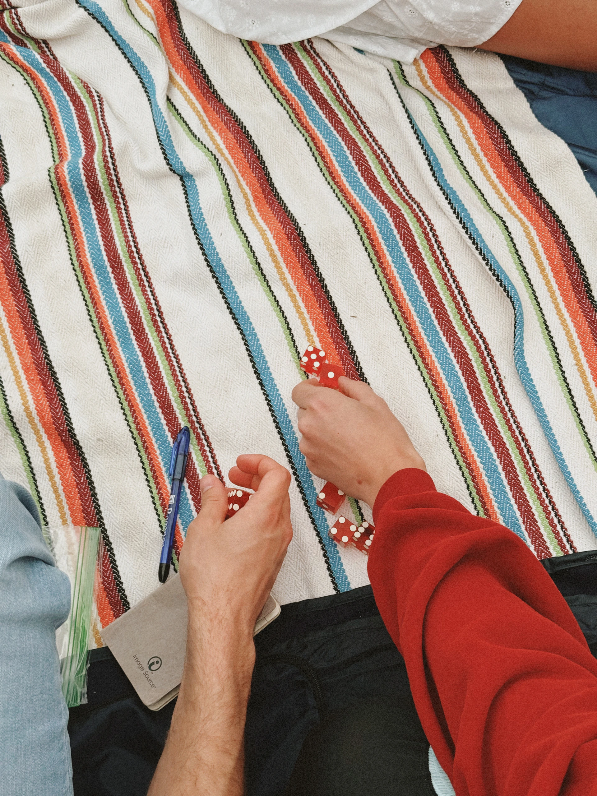 Hands playing with poker chips on a striped blanket