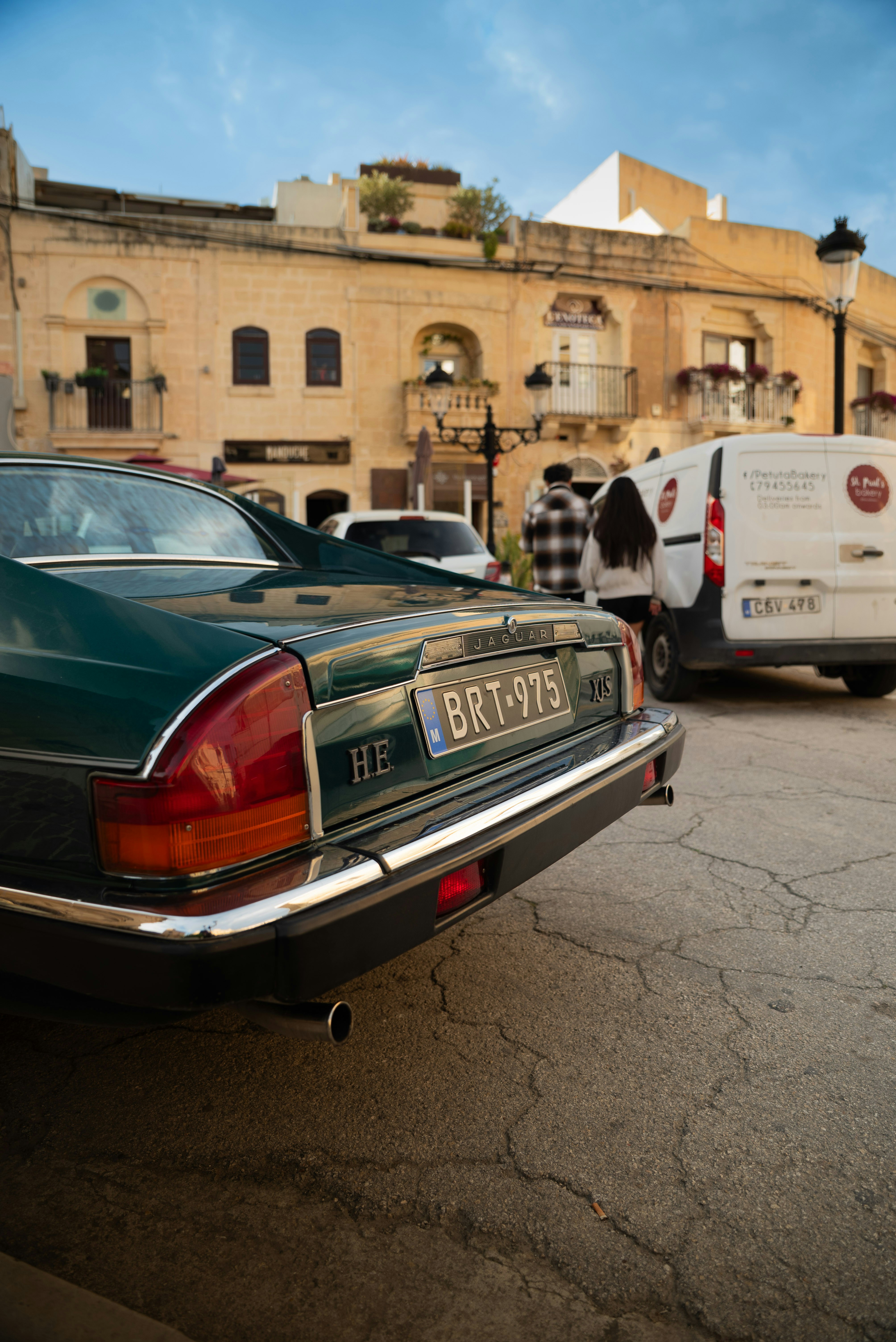 Green vintage car parked on cobblestone street